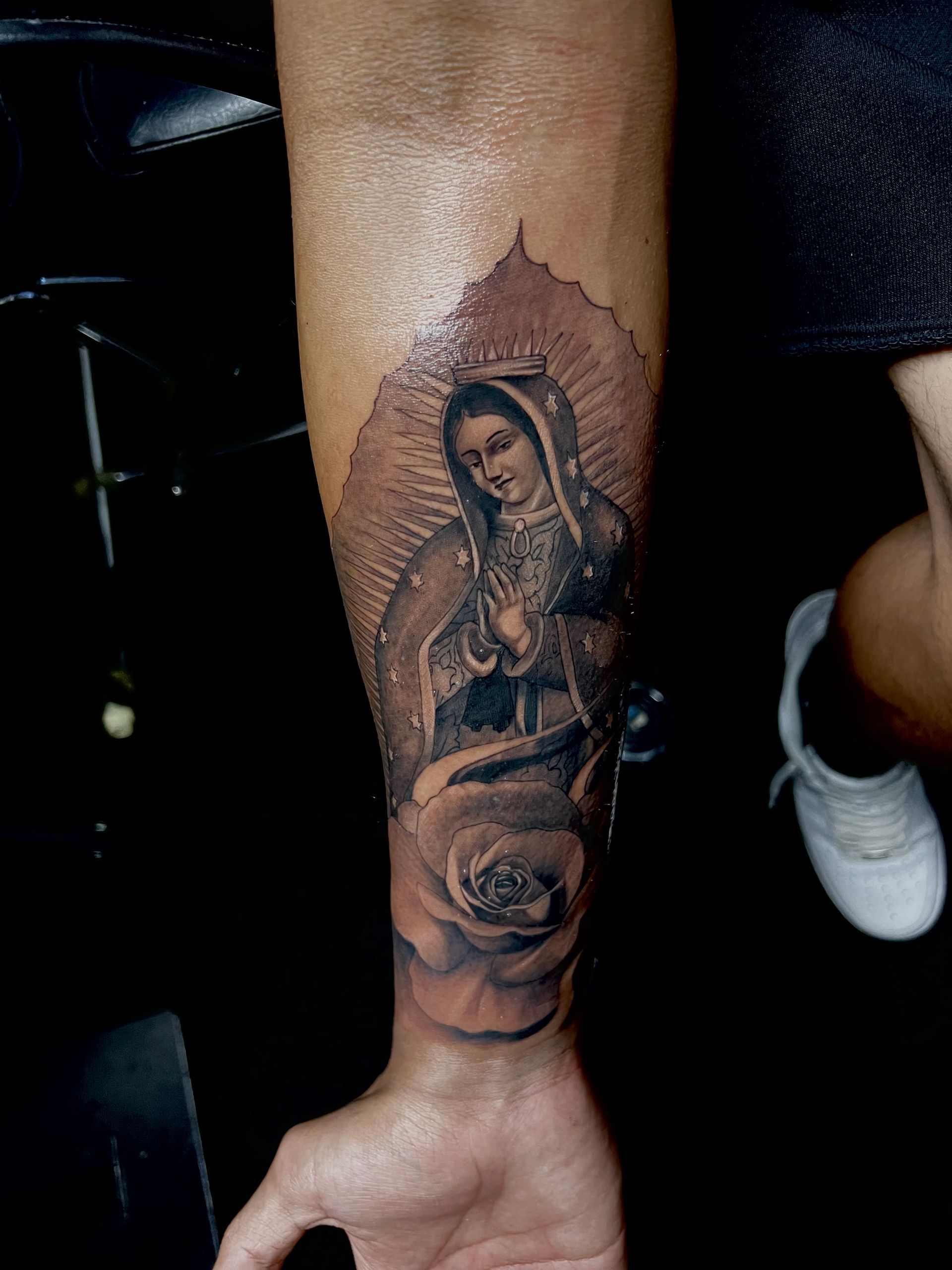 Tattoo of Virgin Mary on forearm, with halo and rose.