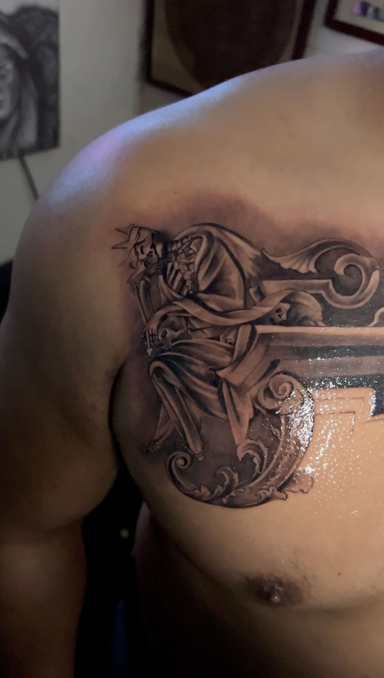 Chest tattoo of a detailed, seated figure with a long beard and ornate scrollwork.