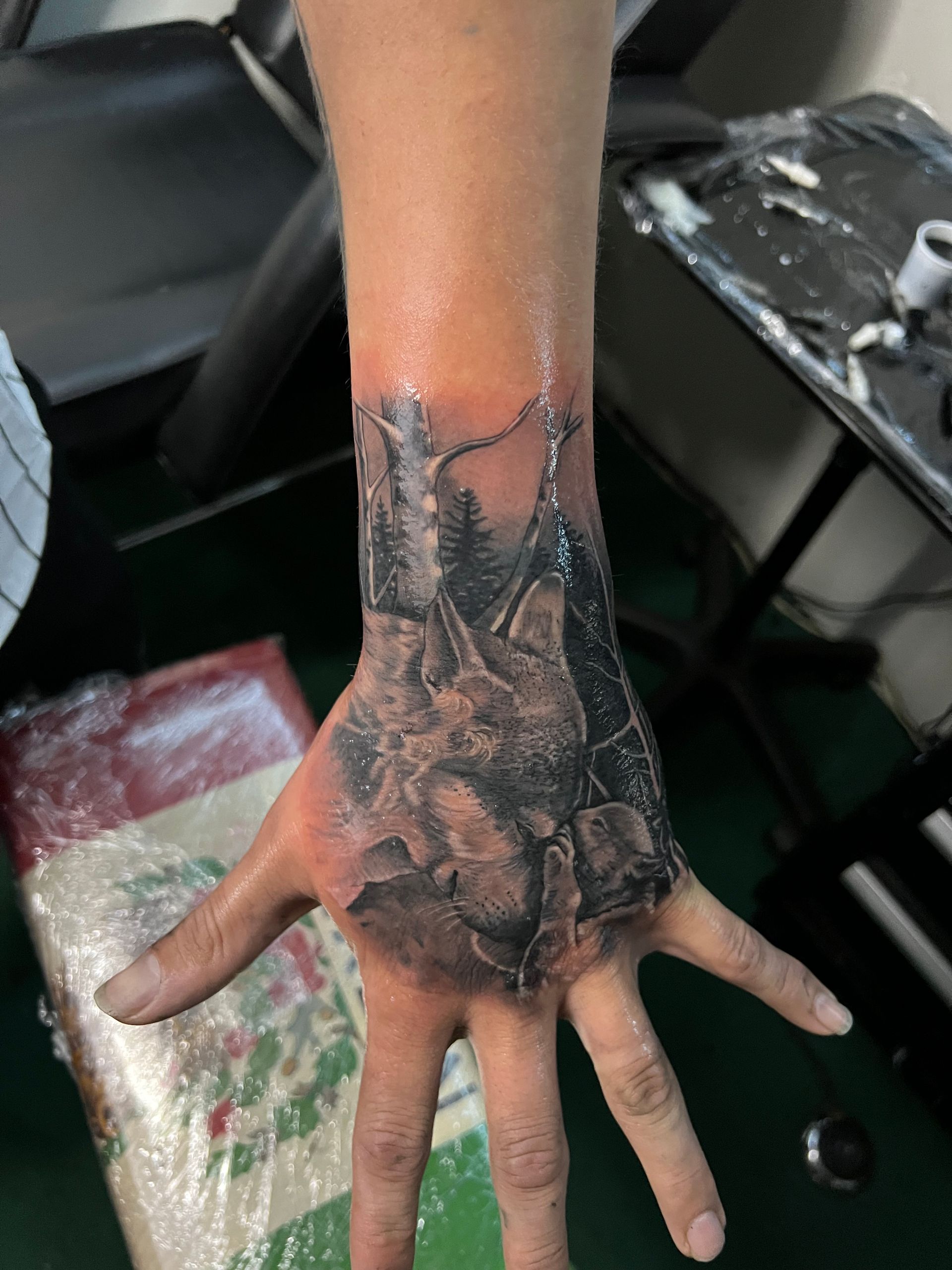 Hand with a detailed, grayscale tattoo of a fortress, mountains, and chains.