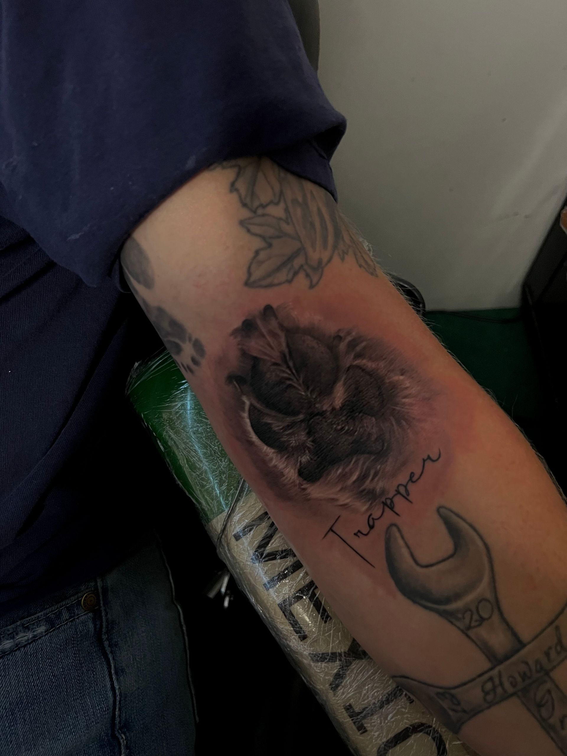 Arm tattoo of a dog paw print with the name