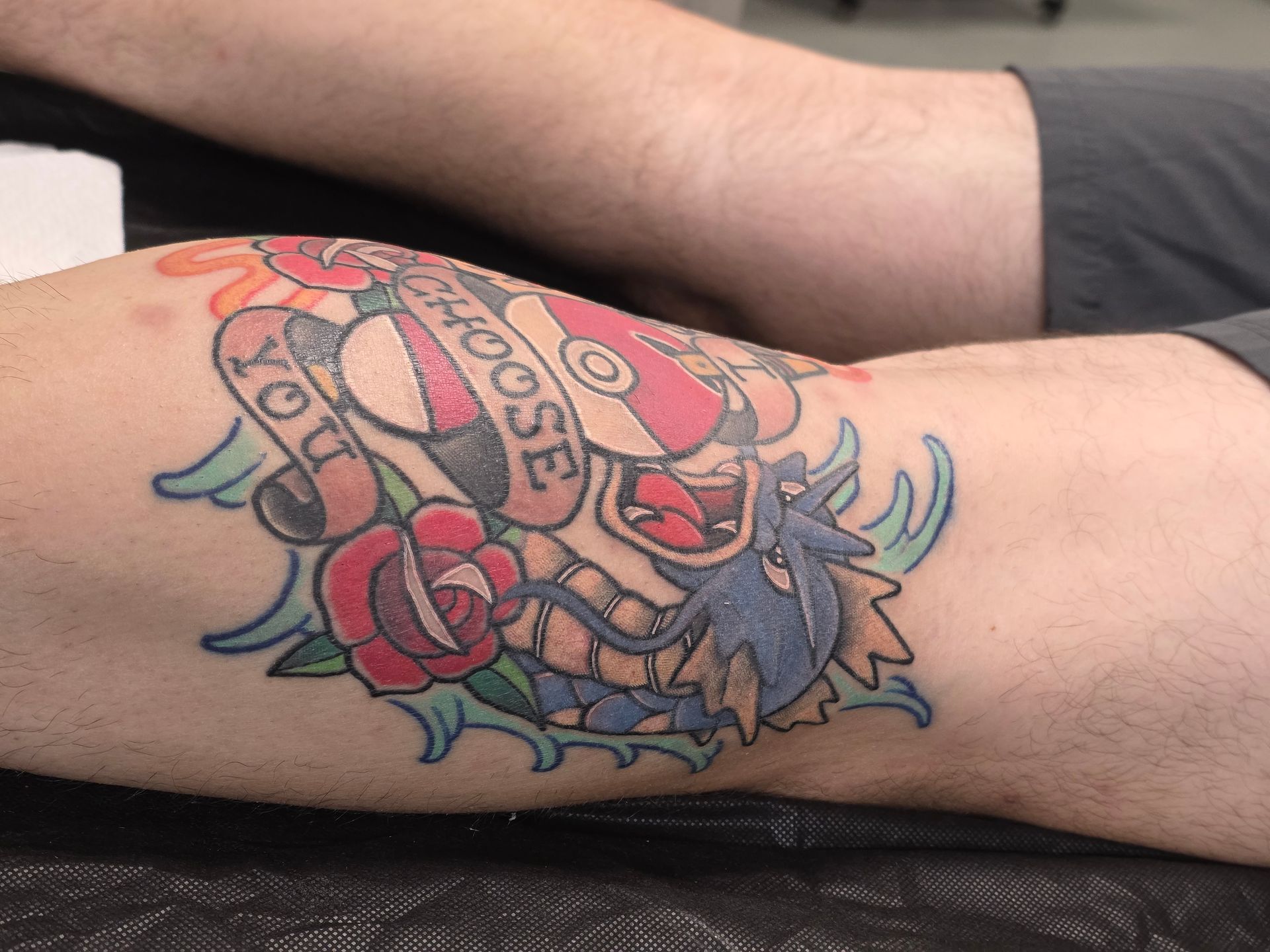 Tattoo of a Gyarados and a Pokéball on a knee, with 