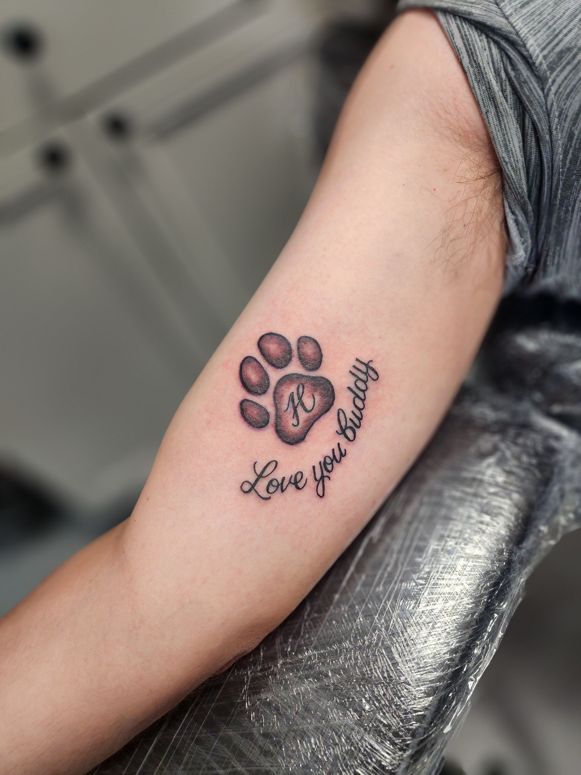 Tattoo of a dog paw print with the letter 
