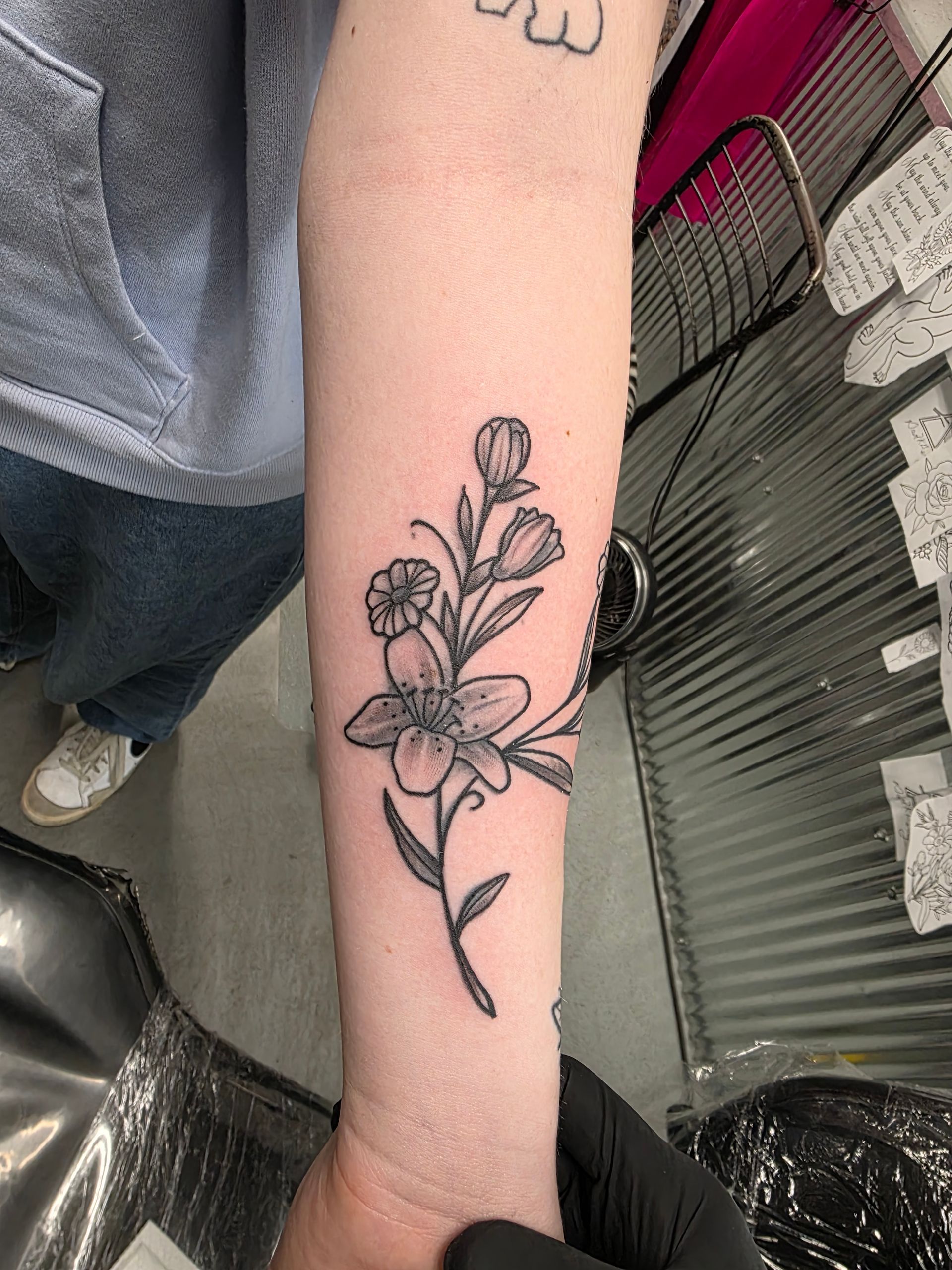 Black line drawing of a floral tattoo on a person's forearm.