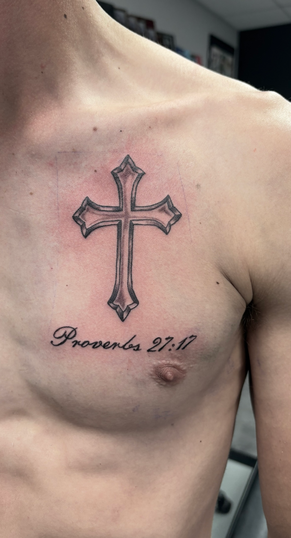 A man has a cross tattoo on his chest.