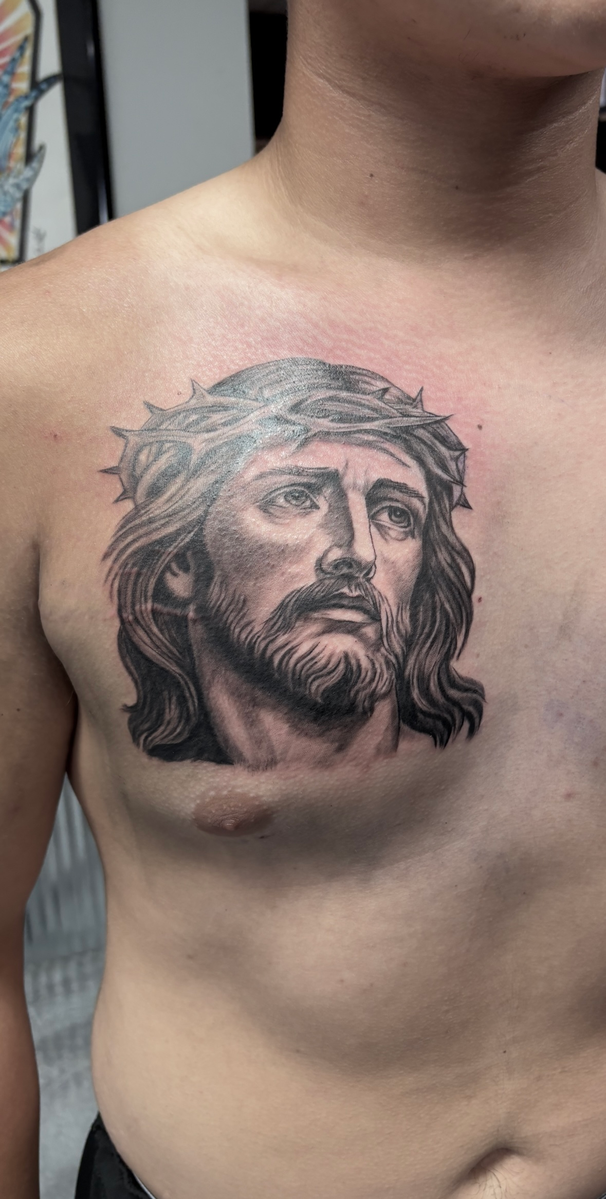 A man has a tattoo of jesus on his chest.