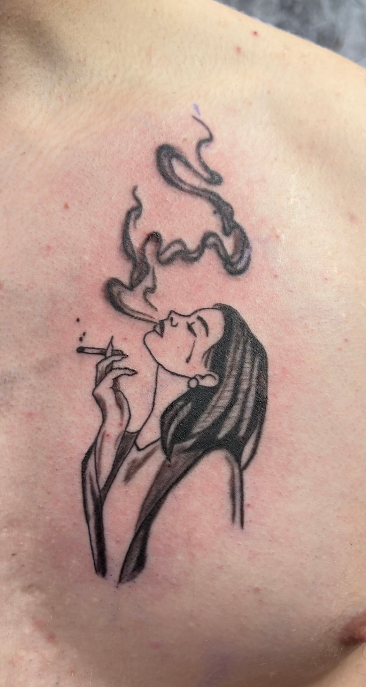 A tattoo that resembles a woman has tears while smoking.
