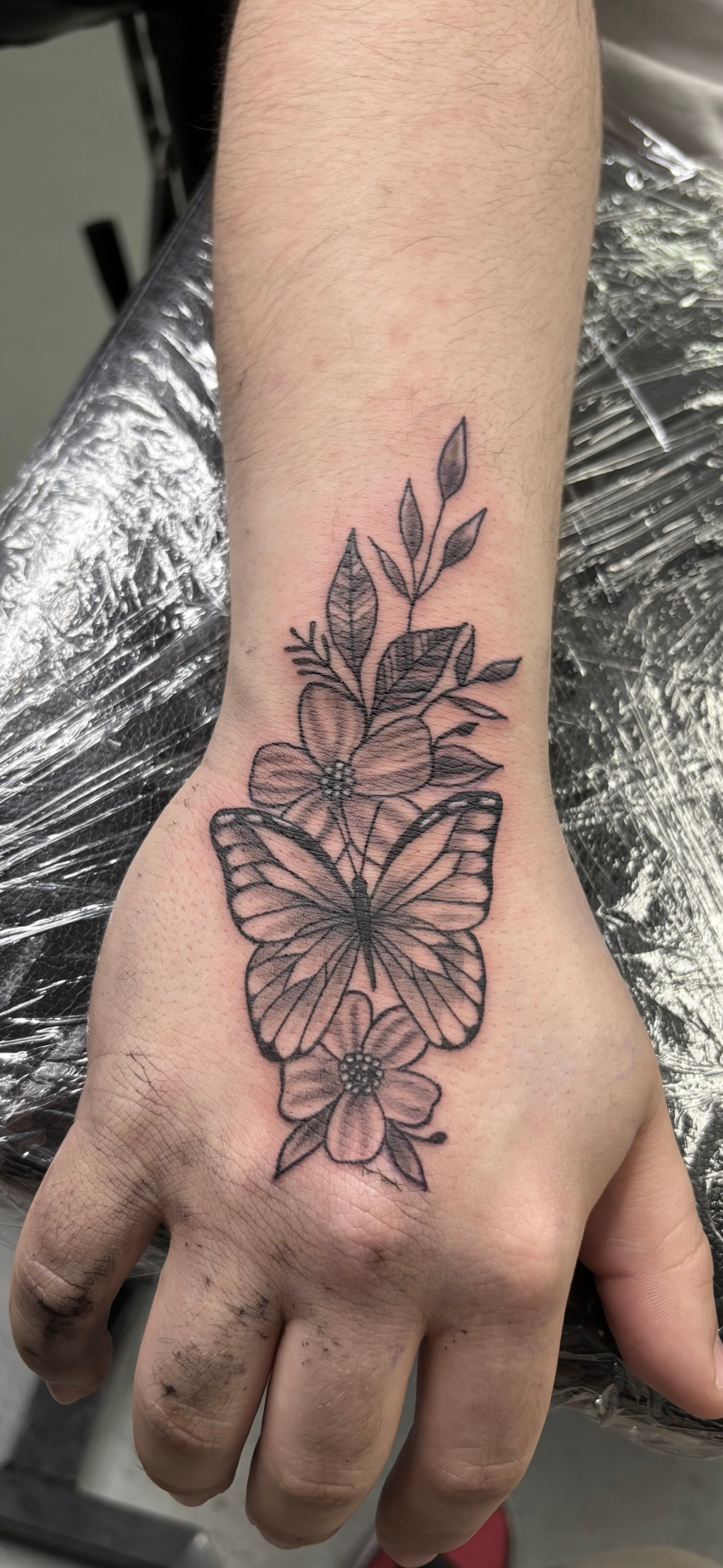 A person has a tattoo of butterflies and flowers on their wrist.