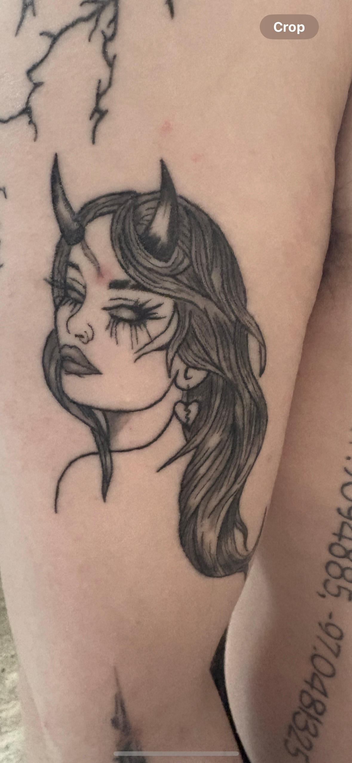 A close up of a tattoo of a woman with horns on her arm.