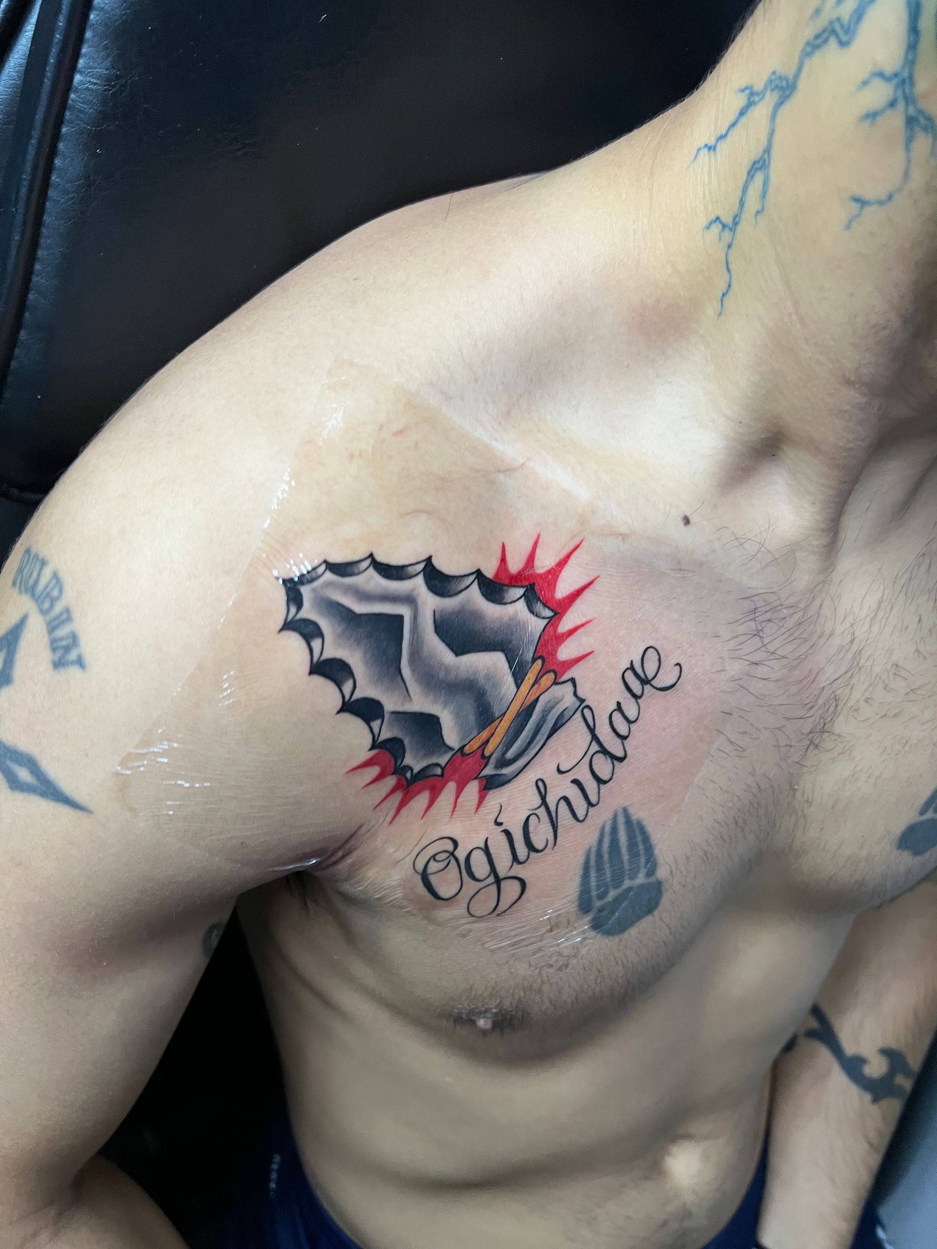 Tattoo on a man's chest: jagged black shape with red border and text