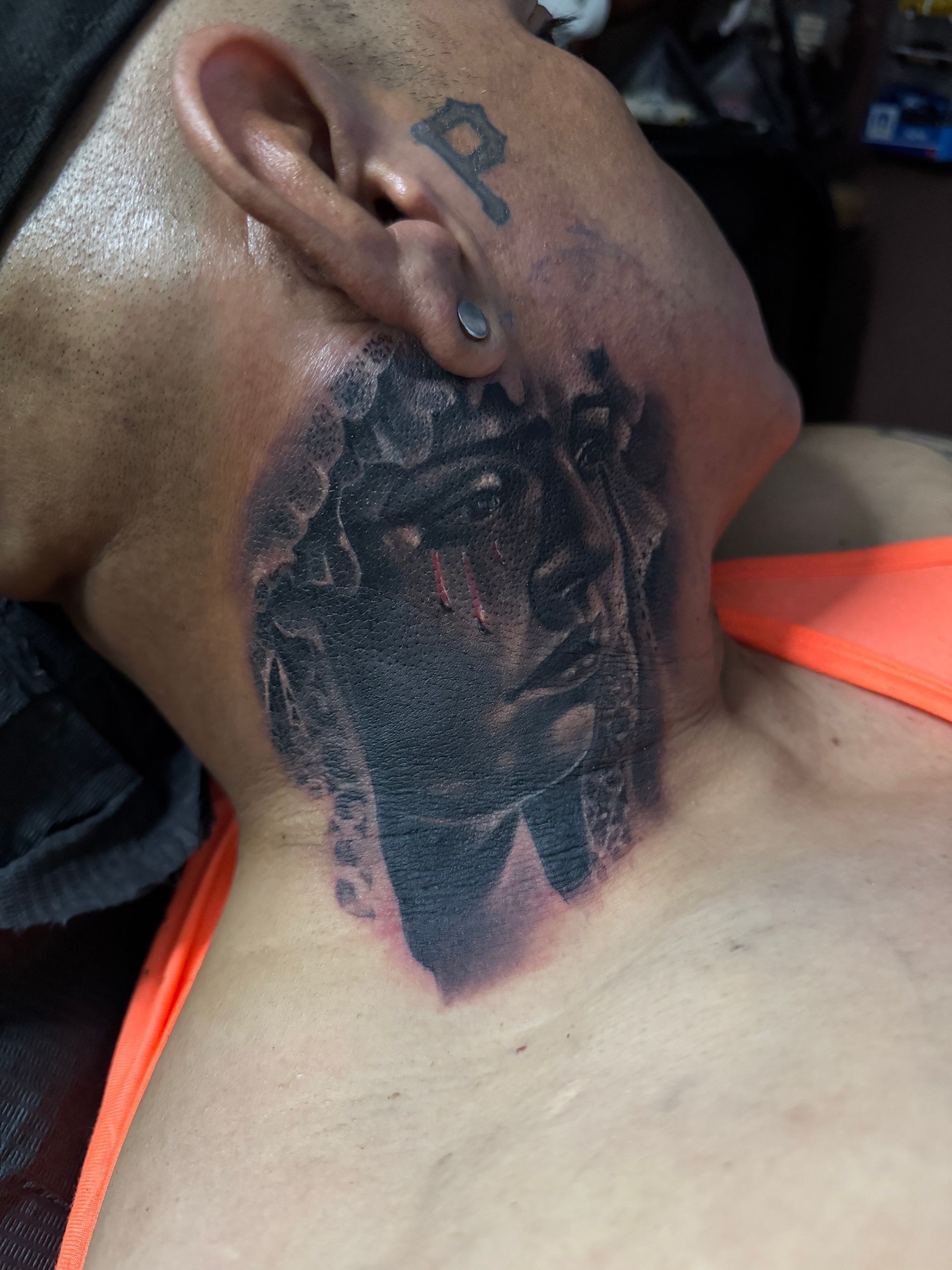 Man's neck tattoo of a dark, blurred image.