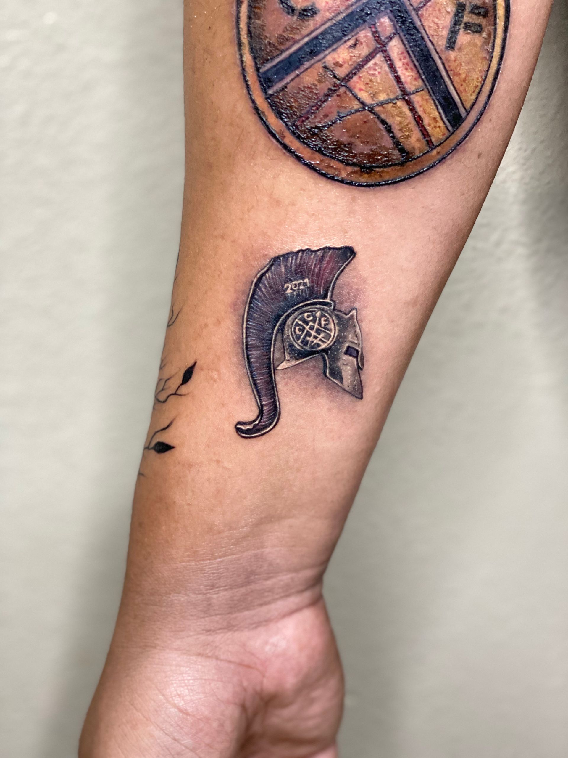 Arm tattoo: Spartan helmet and compass with map design.