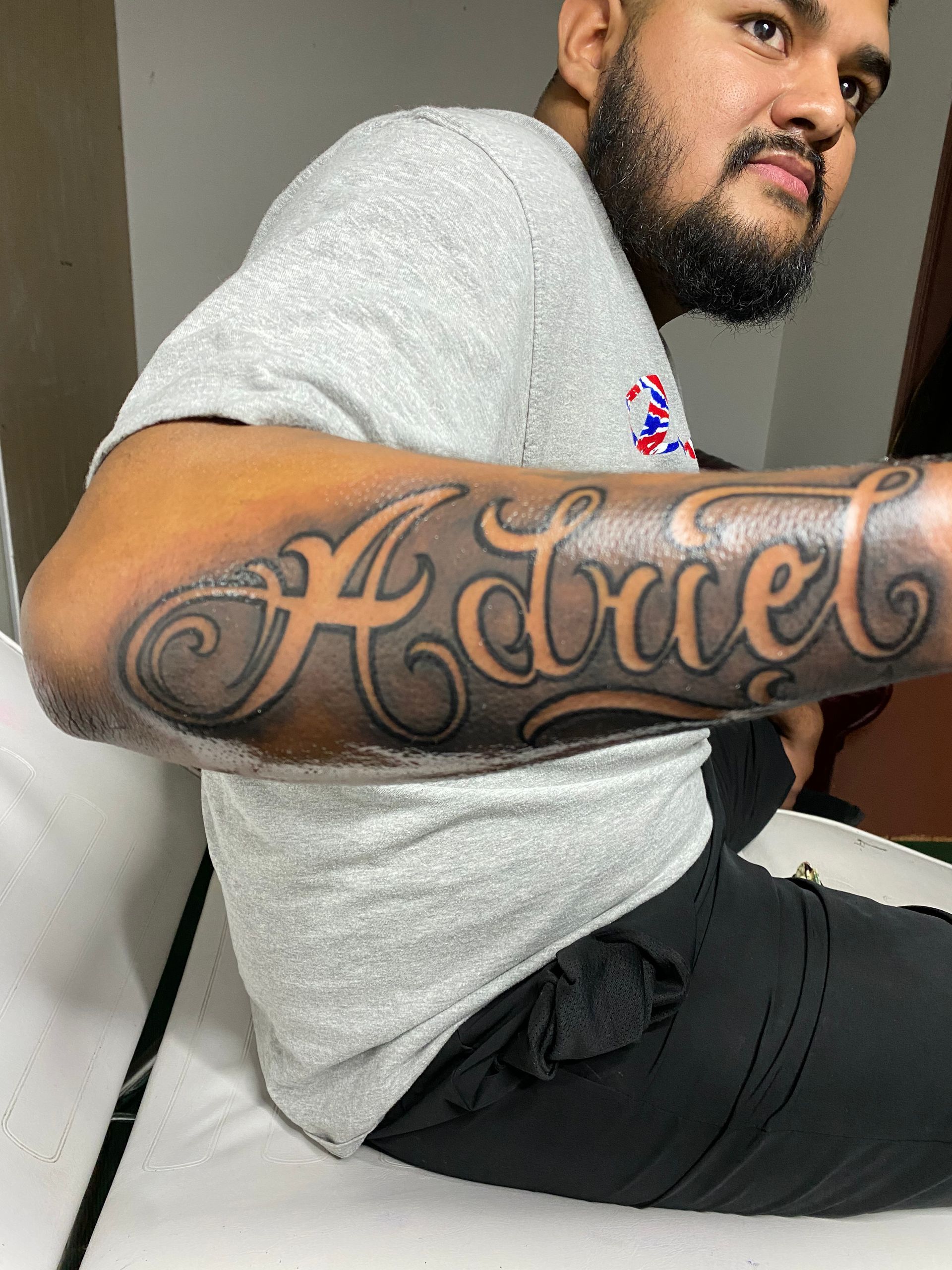 Man with beard shows off a forearm tattoo of the name