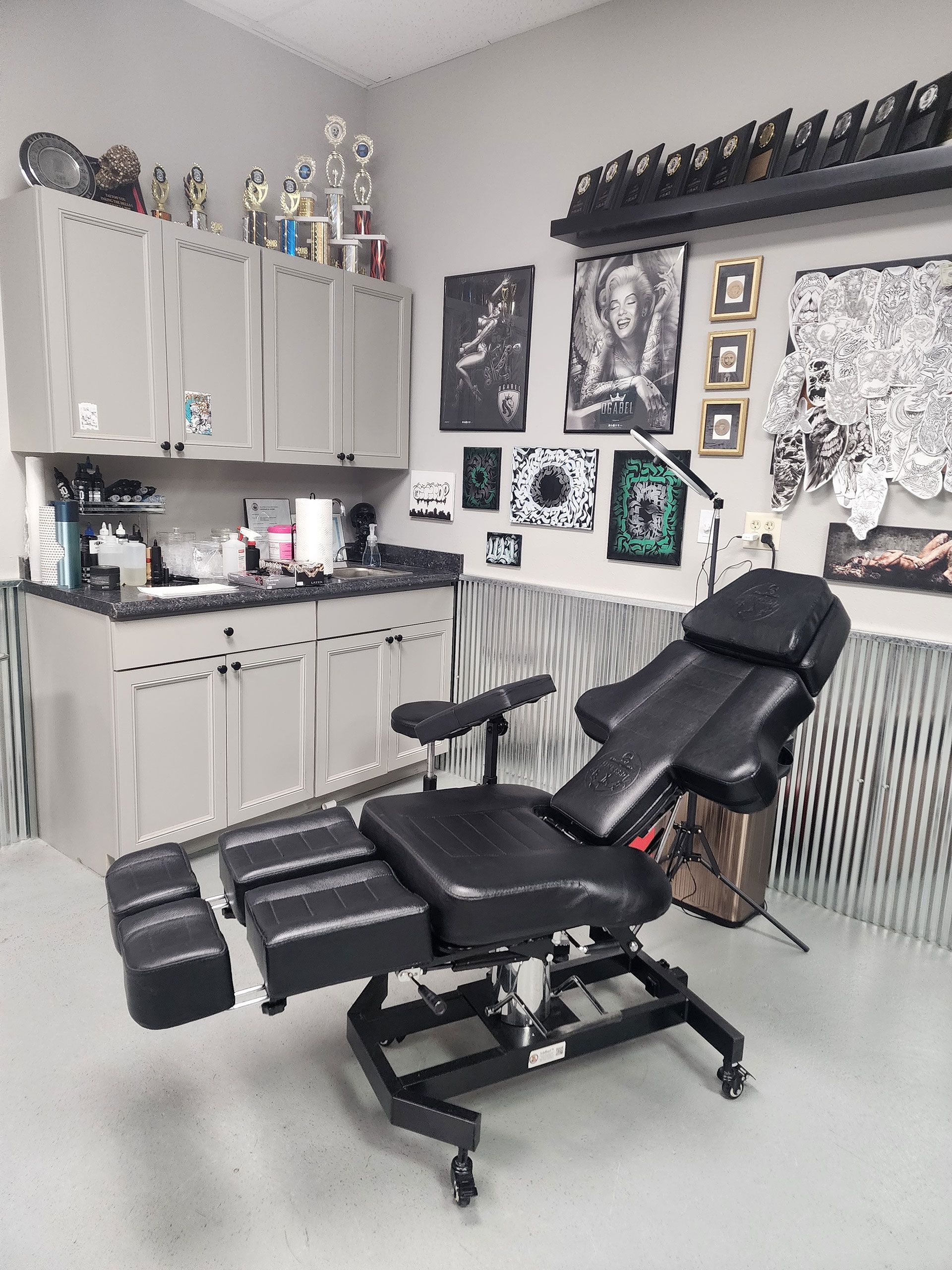 A black chair is sitting in a room with a lot of pictures on the wall.