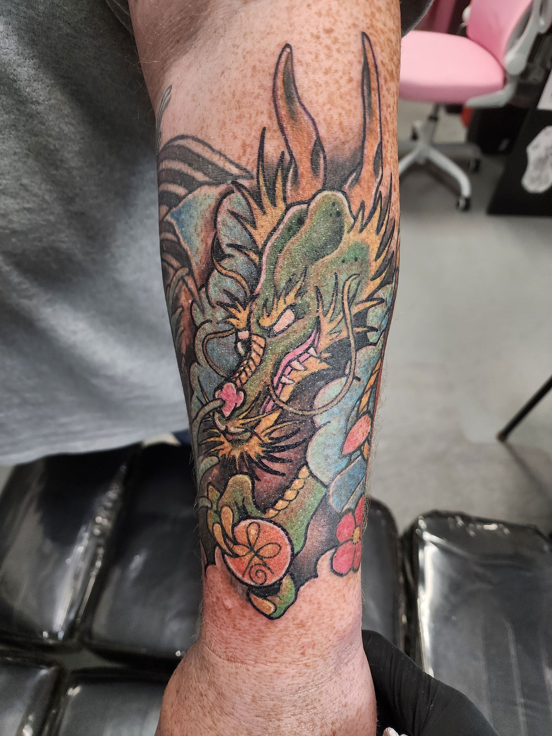 A man has a tattoo of a dragon on his forearm