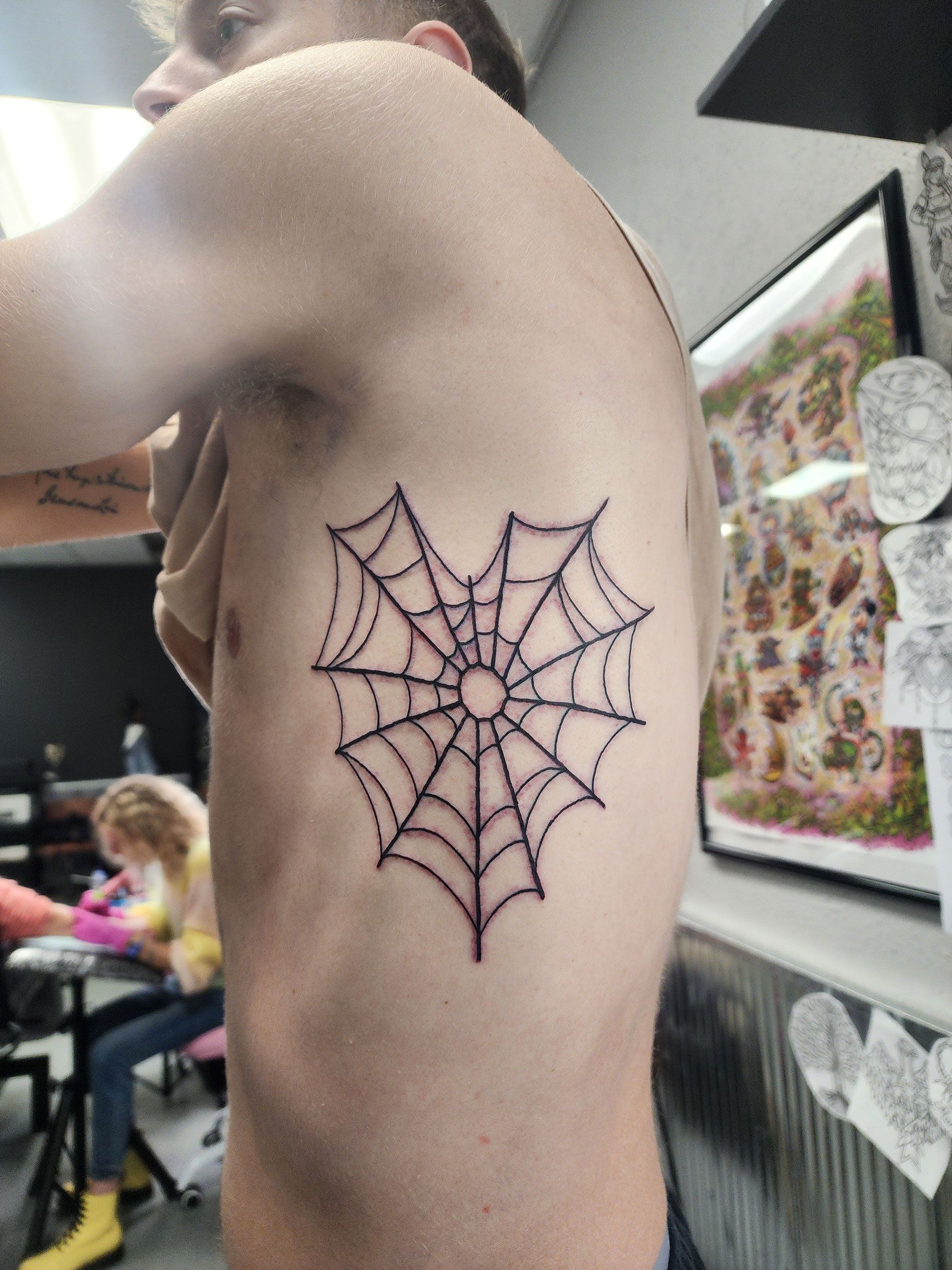 A man has a tattoo of a spider web on his side