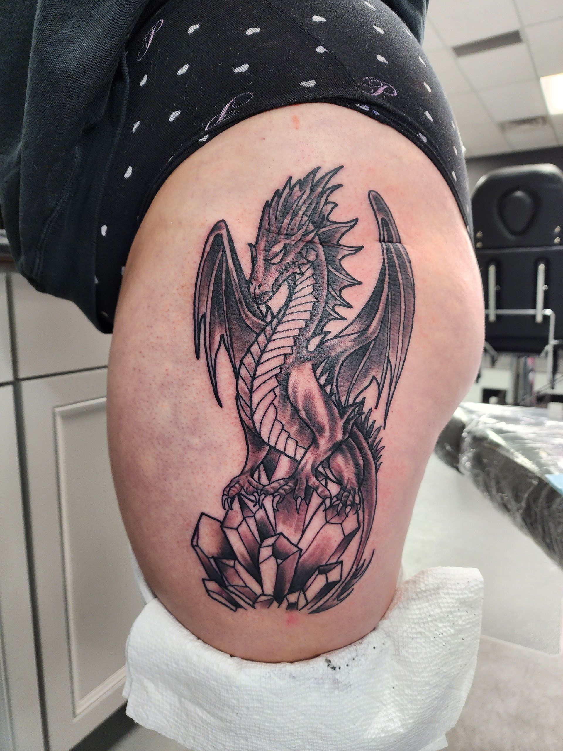 A woman has a tattoo of a dragon on her hip