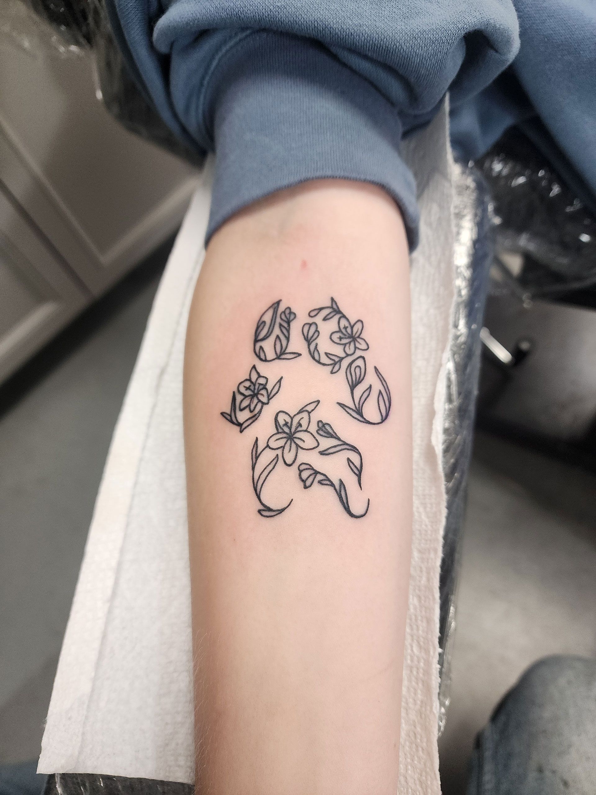 A person has a paw print tattoo on their arm