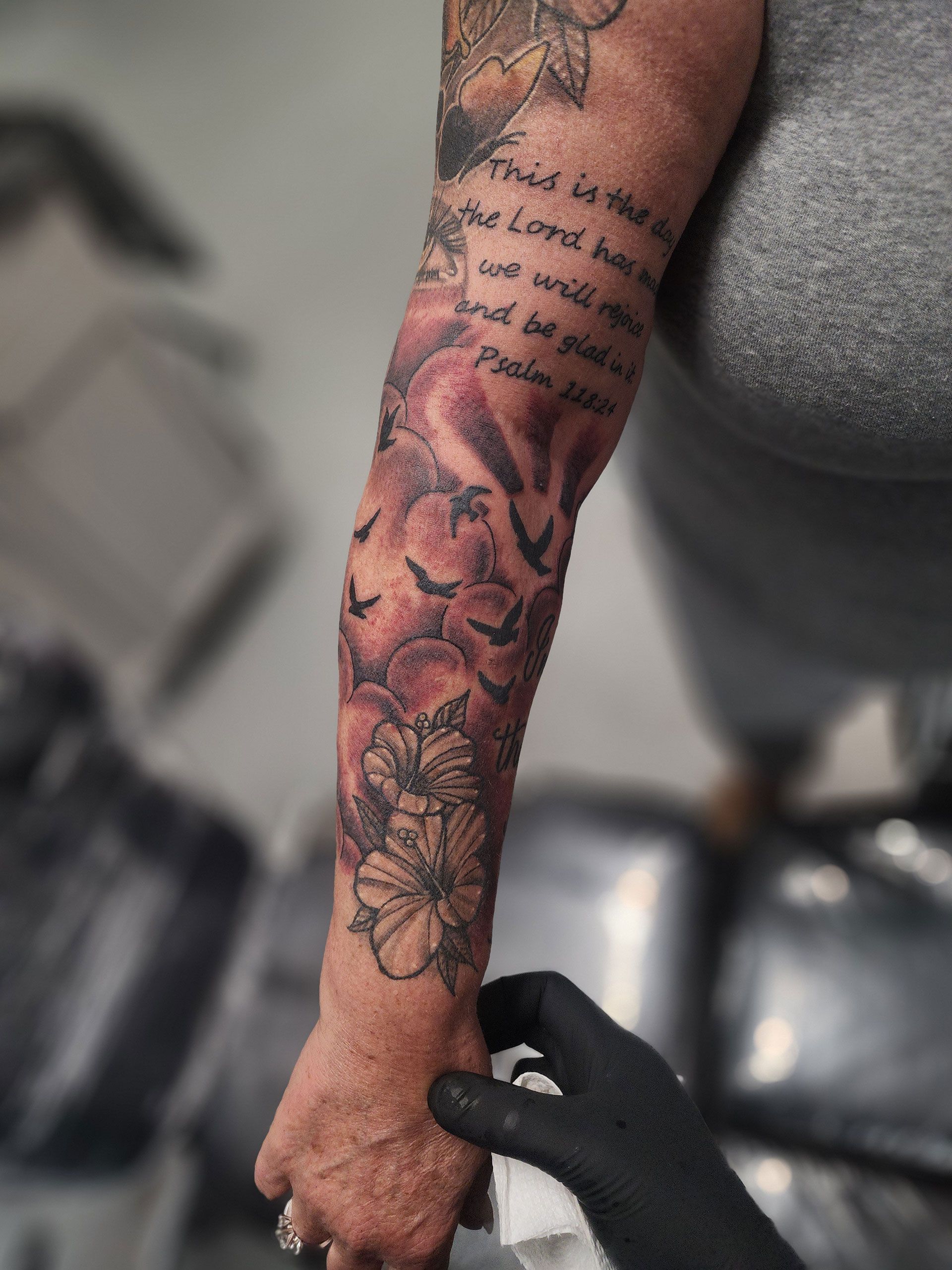 A heavenly themed tattoo with bible verse on the arm