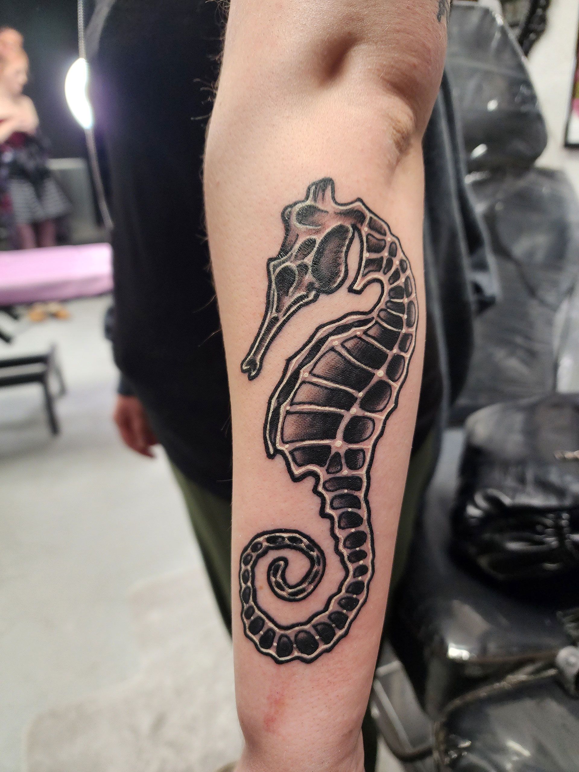 A person has a tattoo of a seahorse on their arm