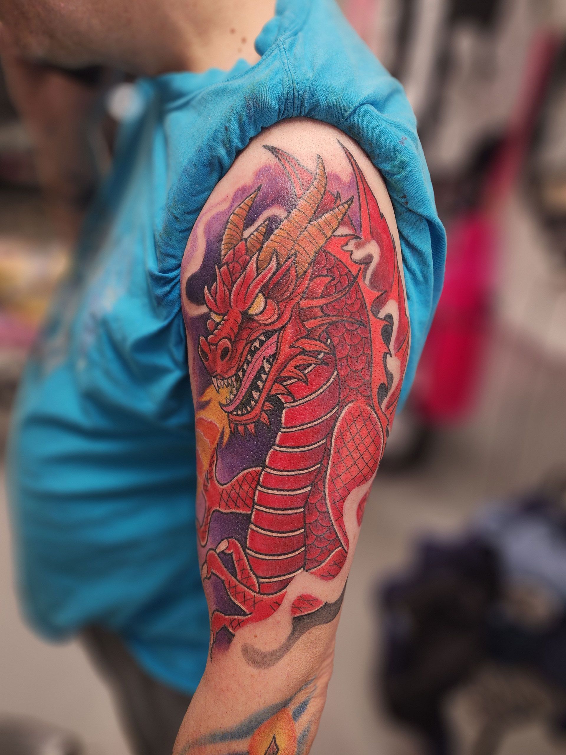 A man has a tattoo of a red dragon on his arm