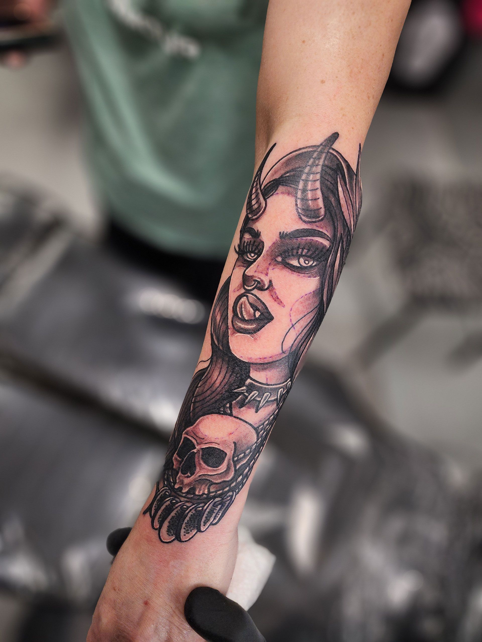 A person has a tattoo of a woman with horns on their forearm