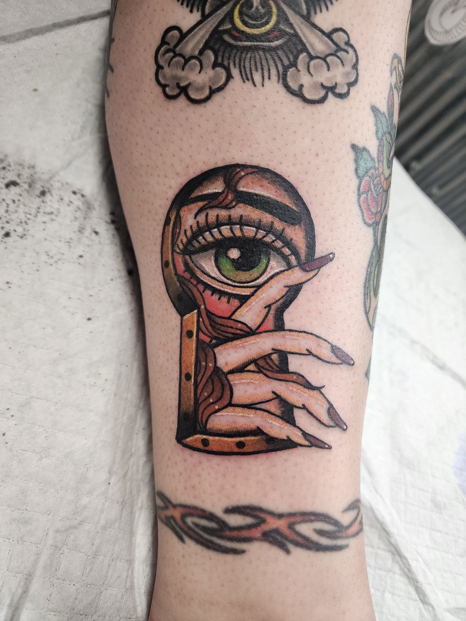 A tattoo of a woman's hand holding a keyhole with an eye in it