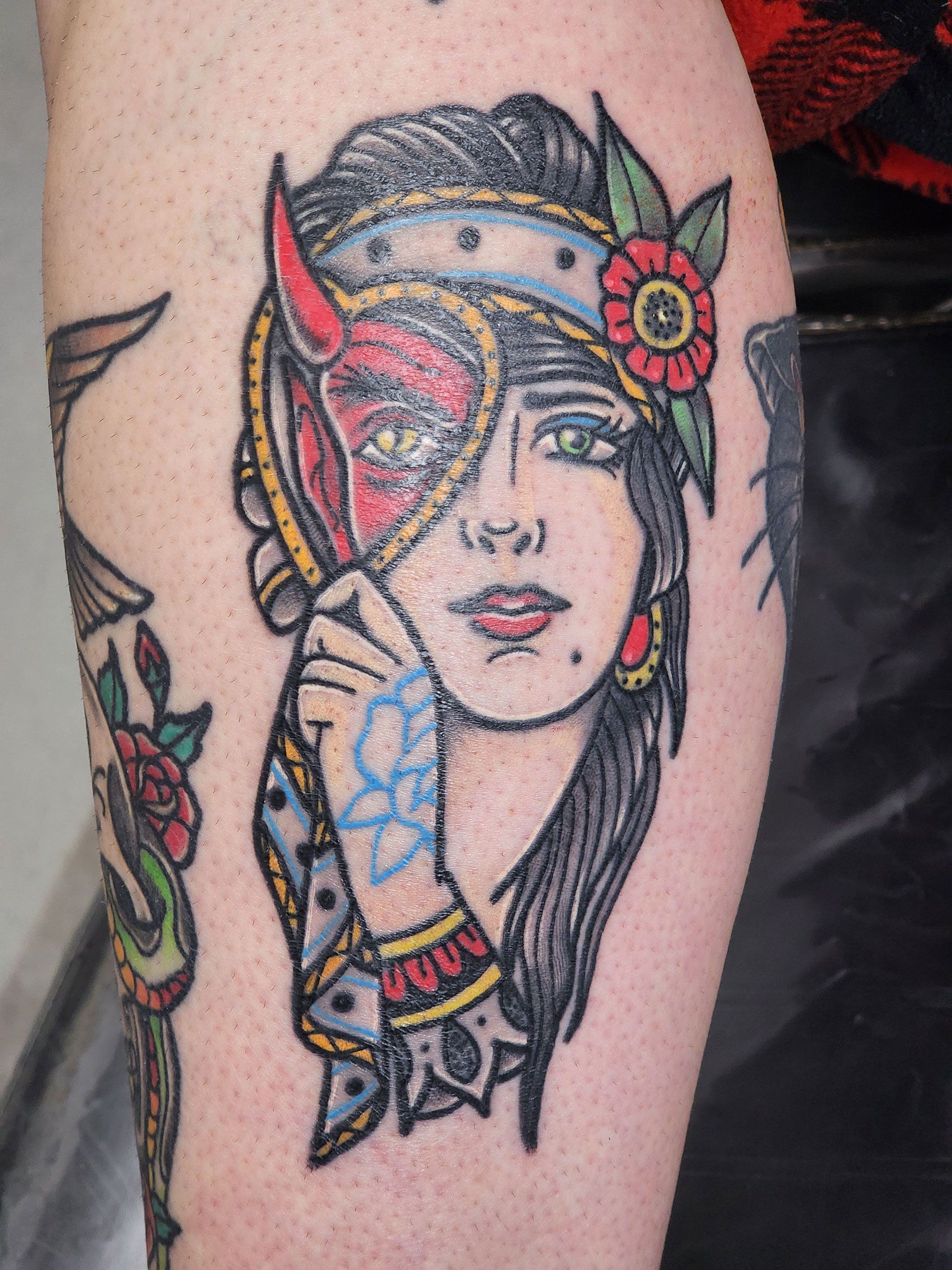 A tattoo of a woman with a devil mask on her face