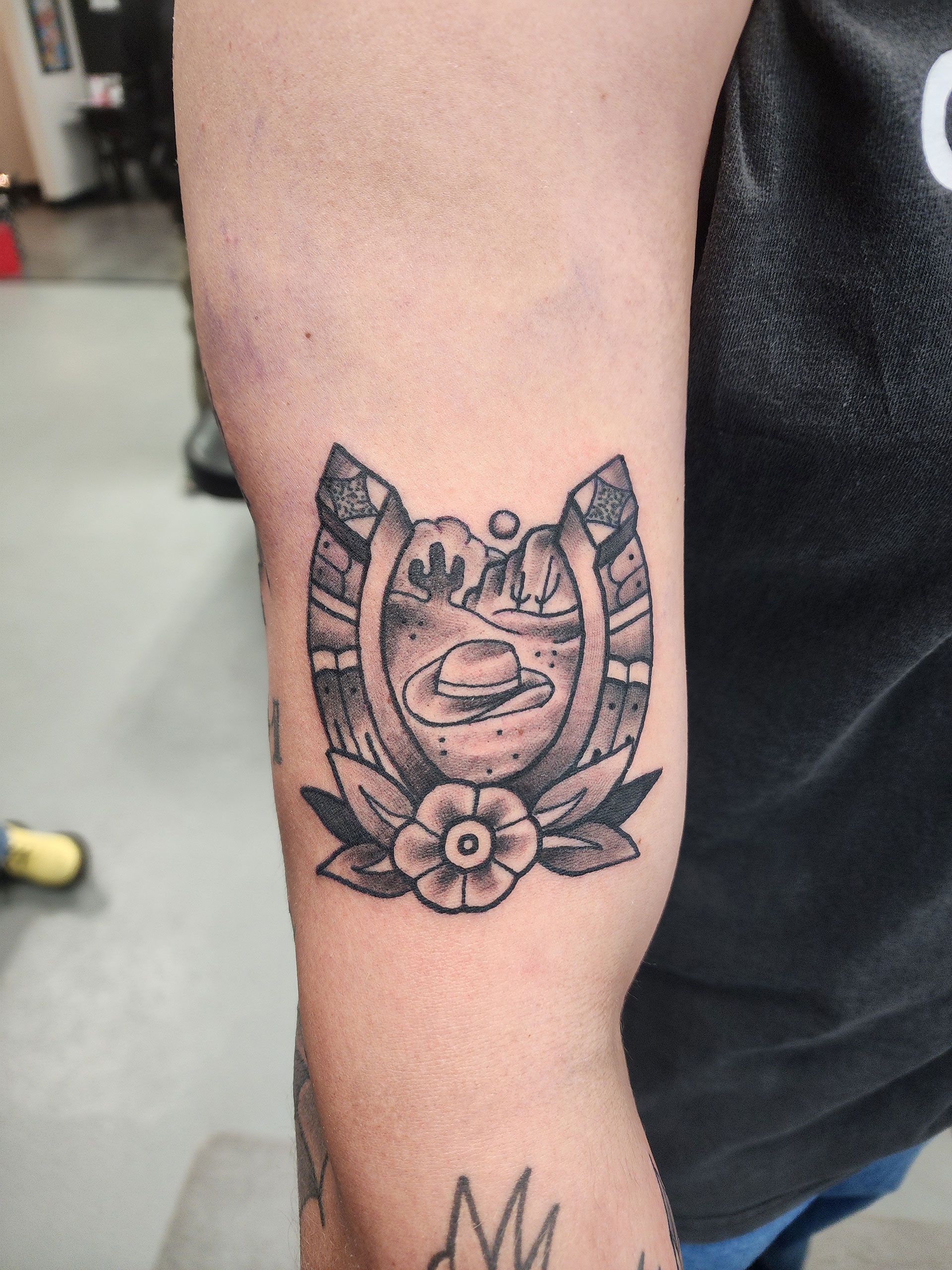 A person has a horseshoe tattoo on their arm