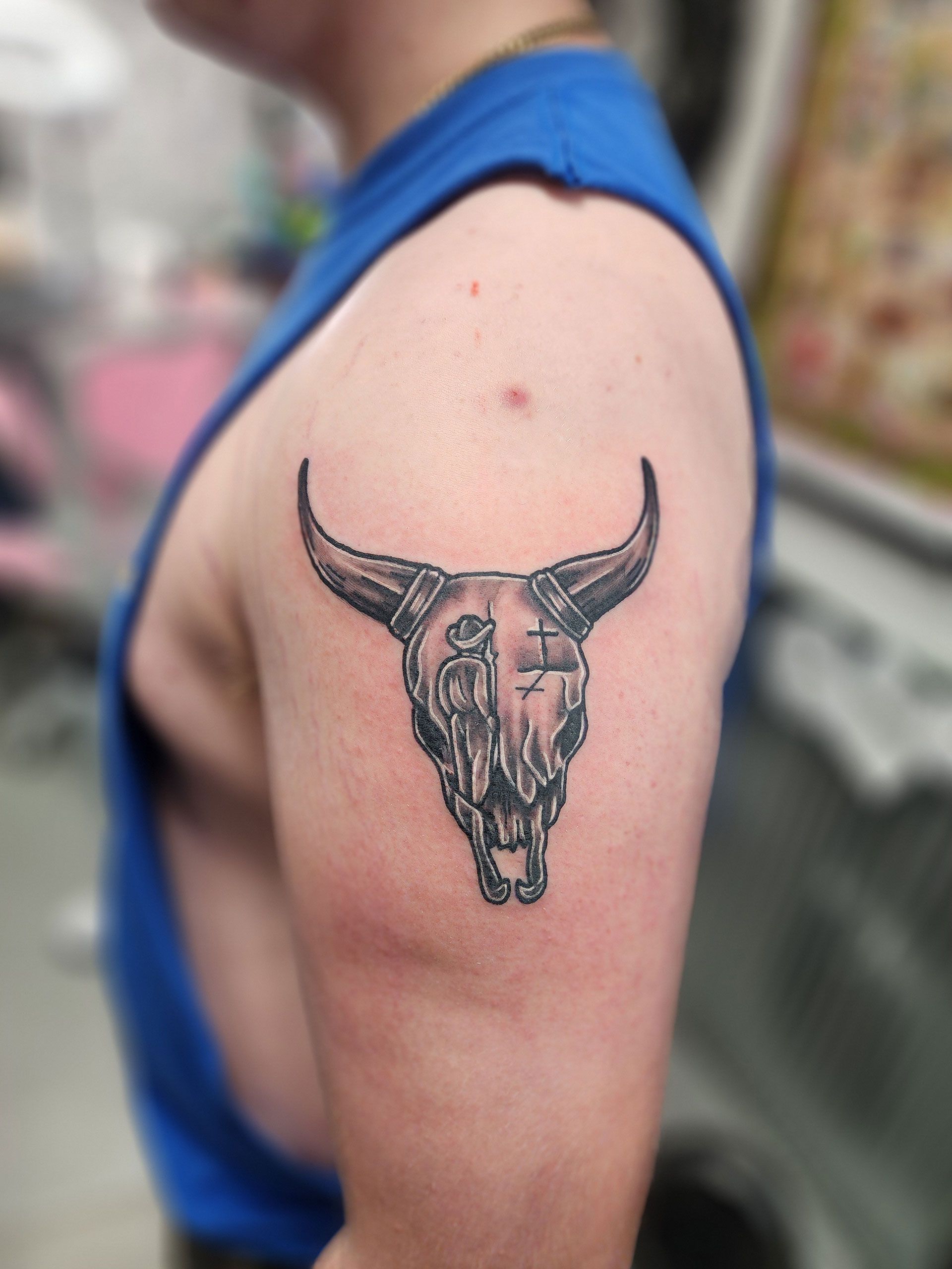 A man has a tattoo of a bull skull on his arm