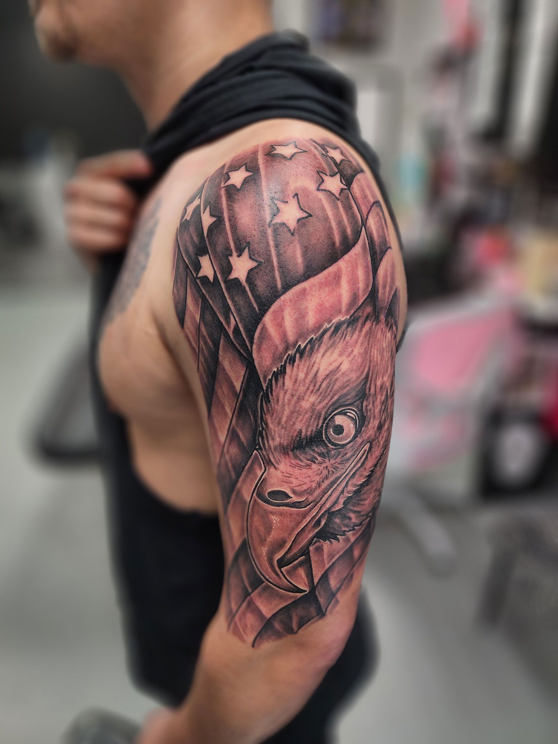 A man has a tattoo of an eagle over the American flag on his arm