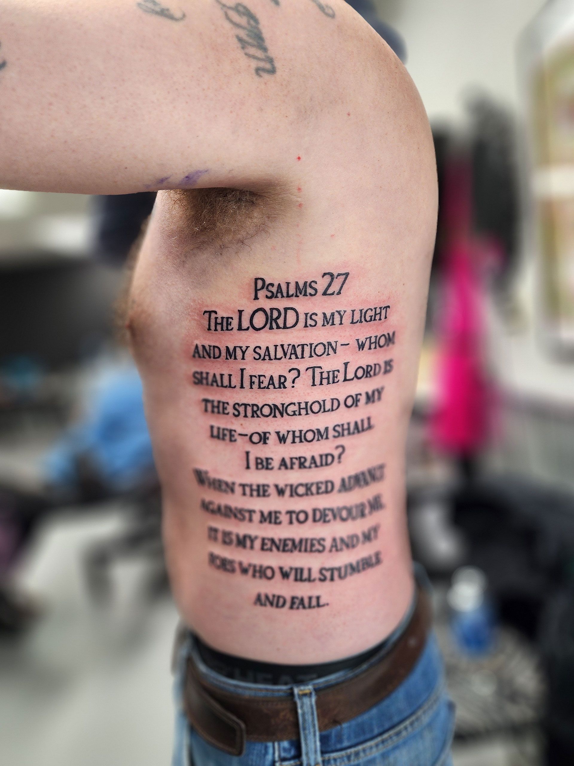 A man has a tattoo of psalms 27 on his side