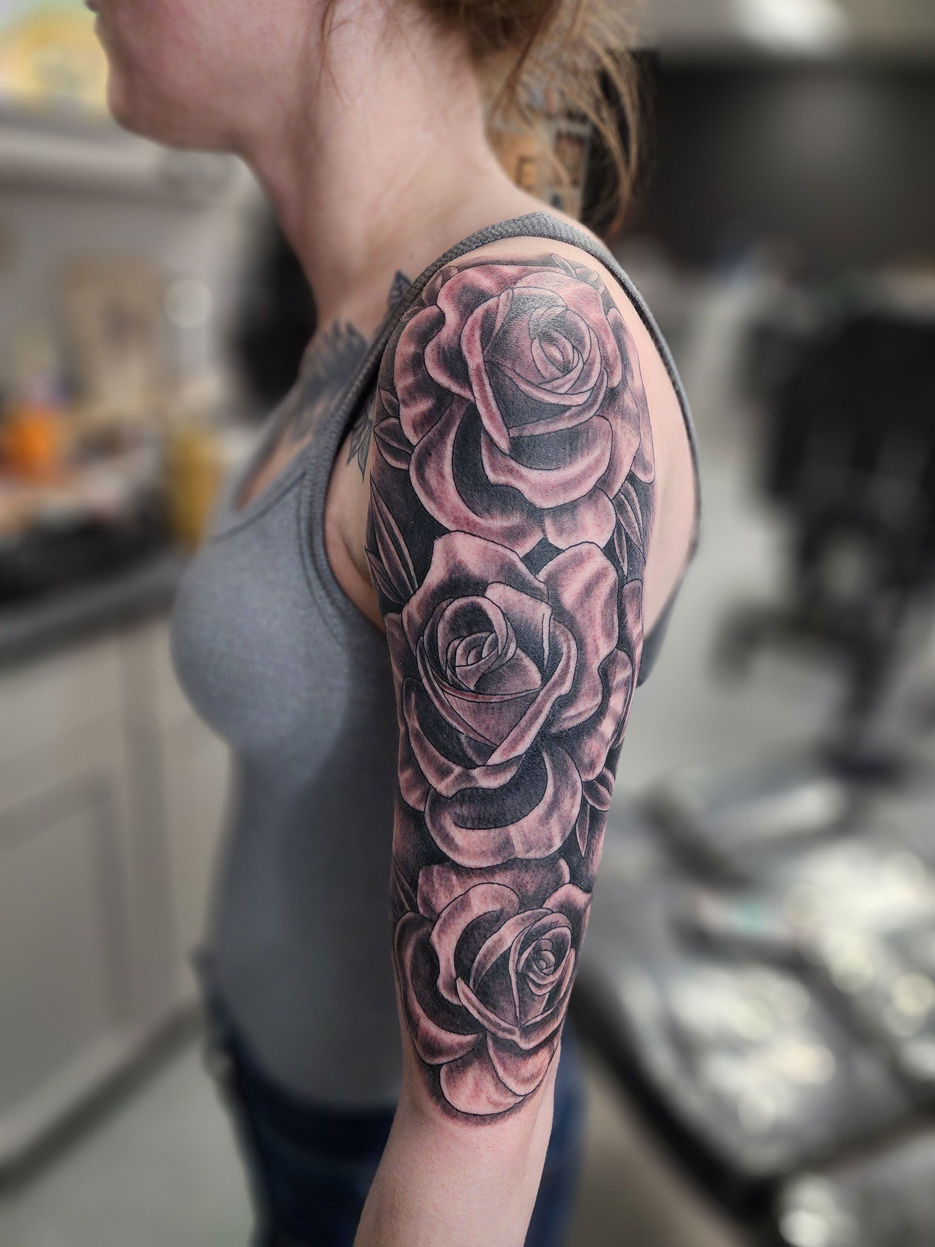 A woman has a tattoo of three roses on her arm