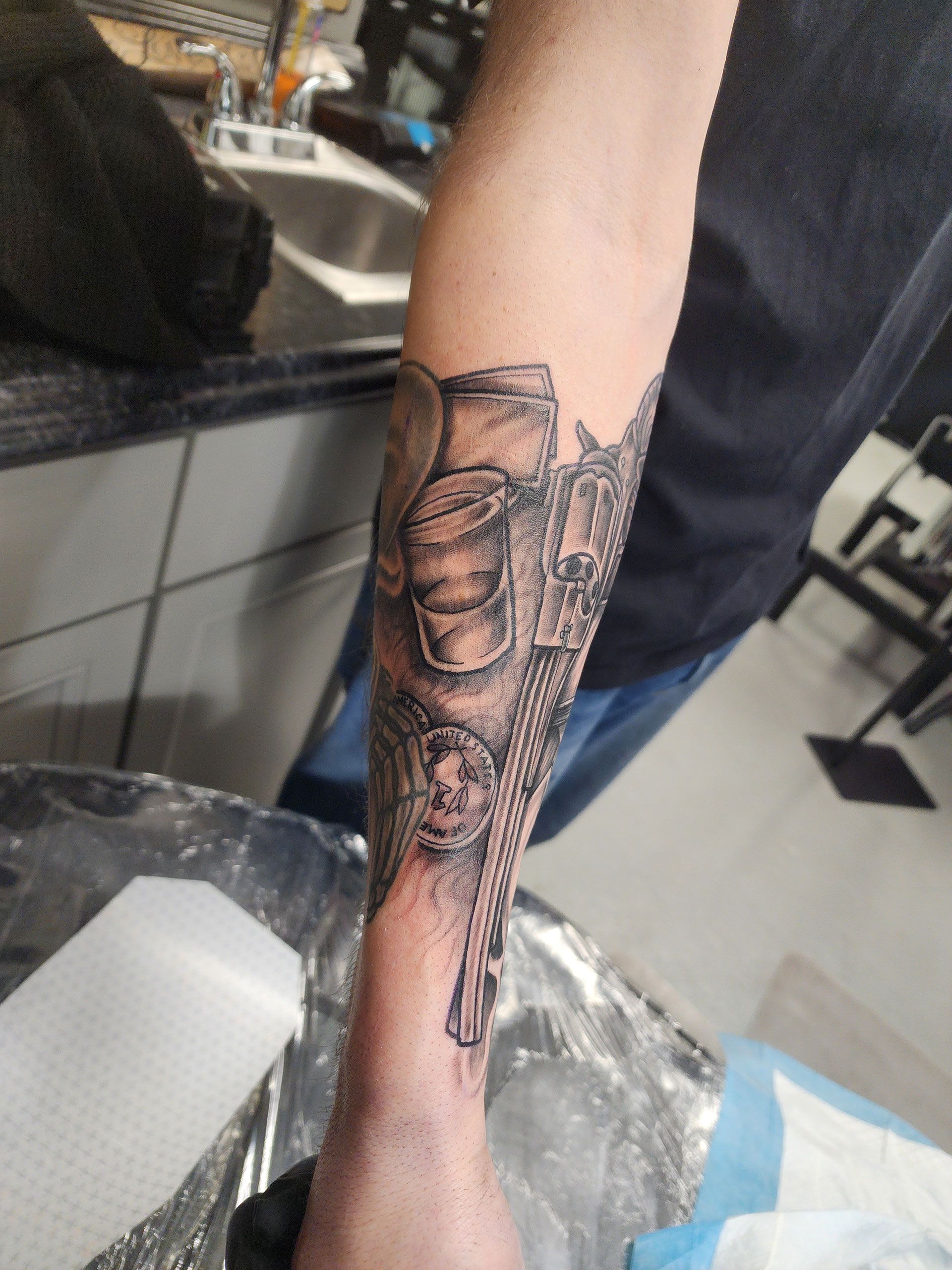 A man with gun, cards, coins, and drink tattoo on his arm