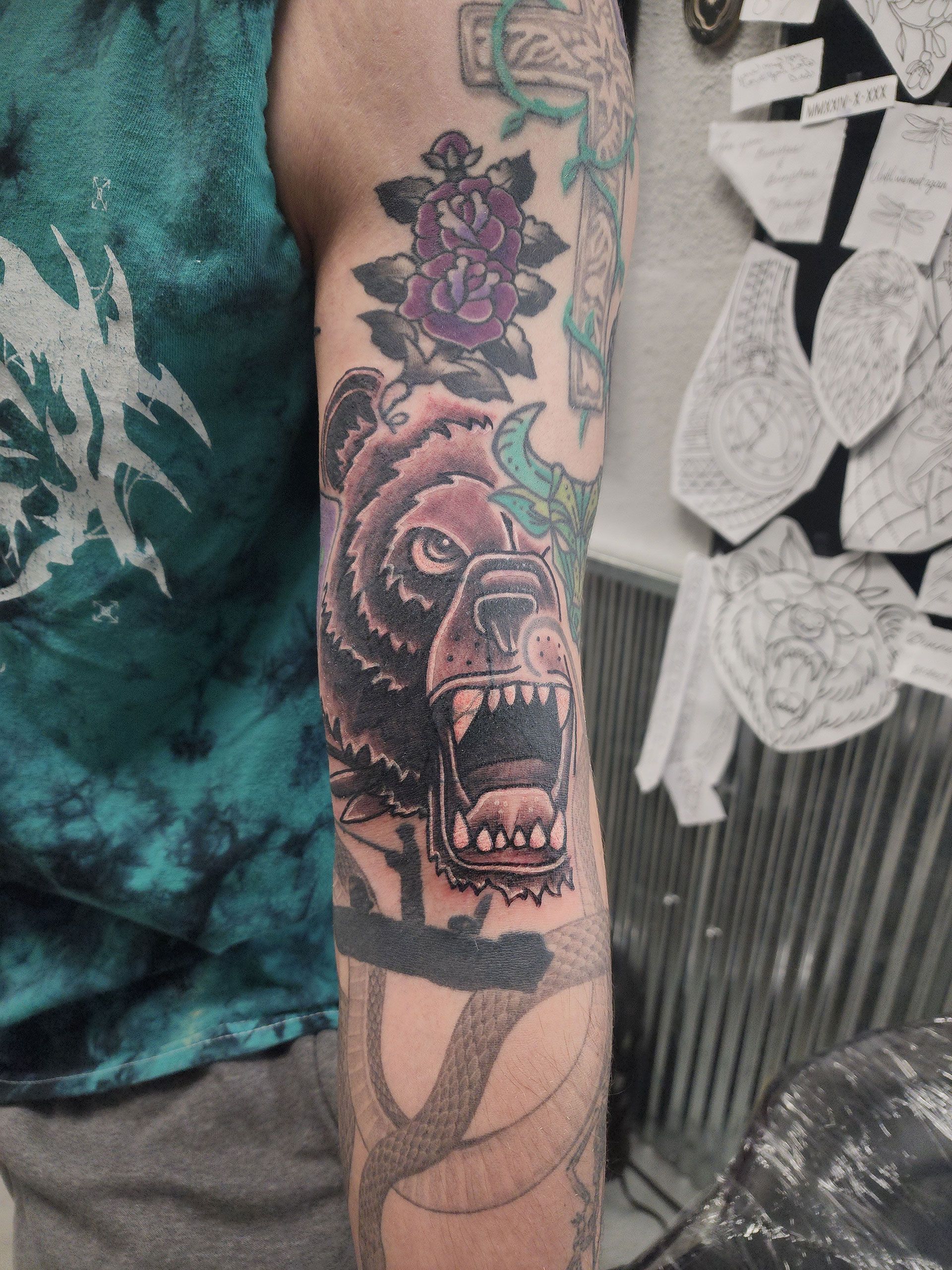 A man has a tattoo of a bear and a rose on his arm