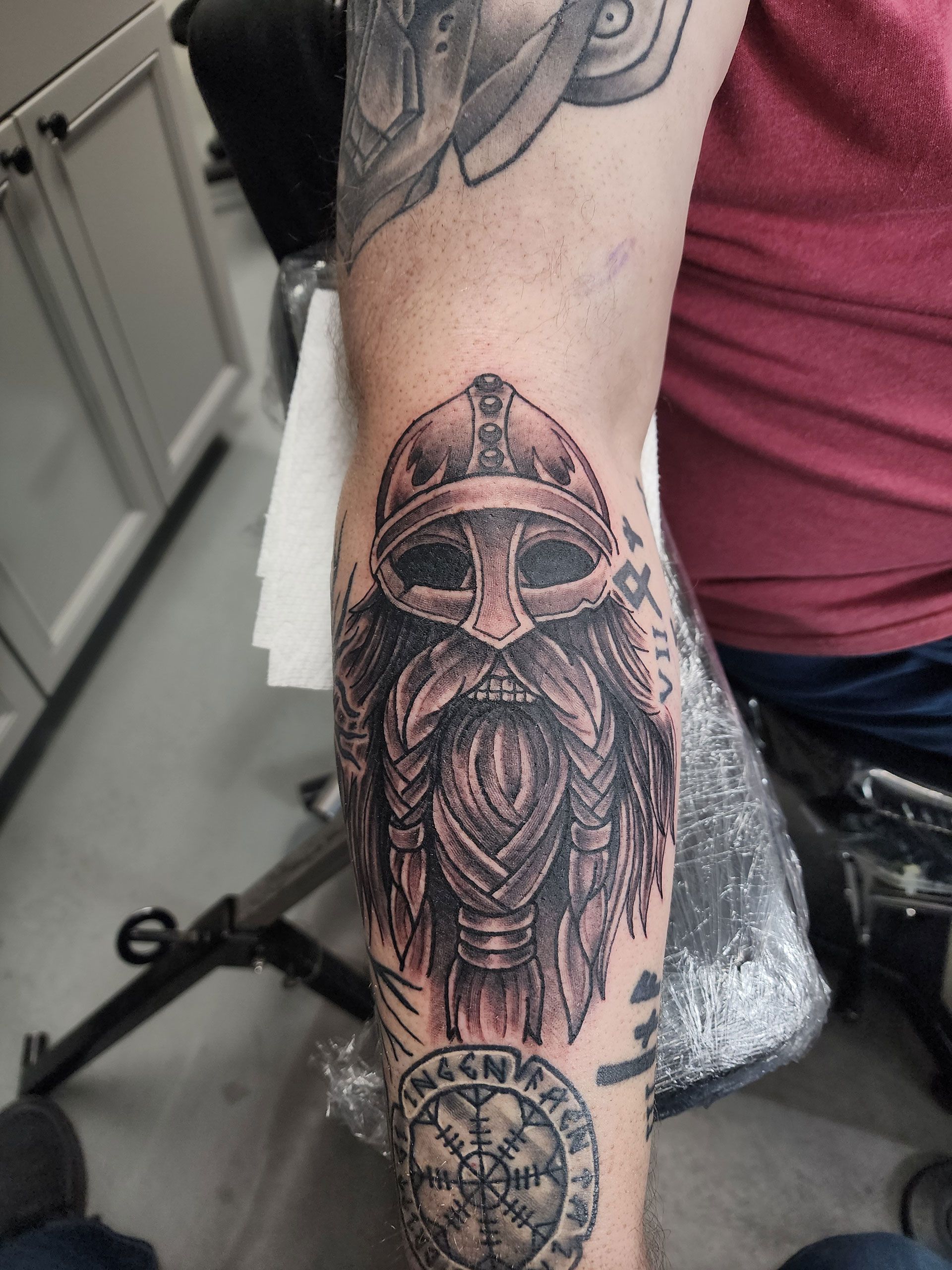 A man has a tattoo of a Viking on his arm