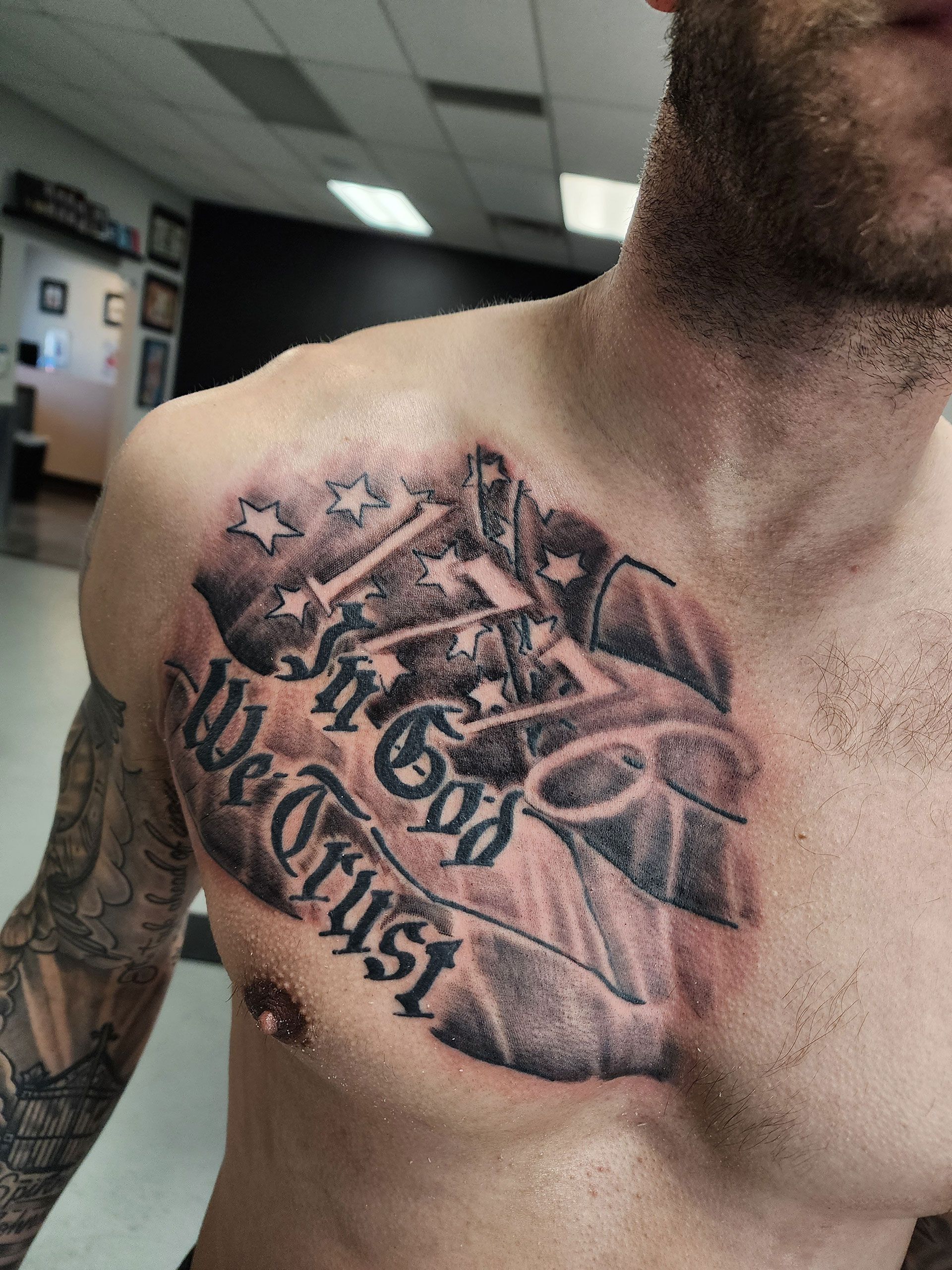 A man has a tattoo on his chest that says in god we trust
