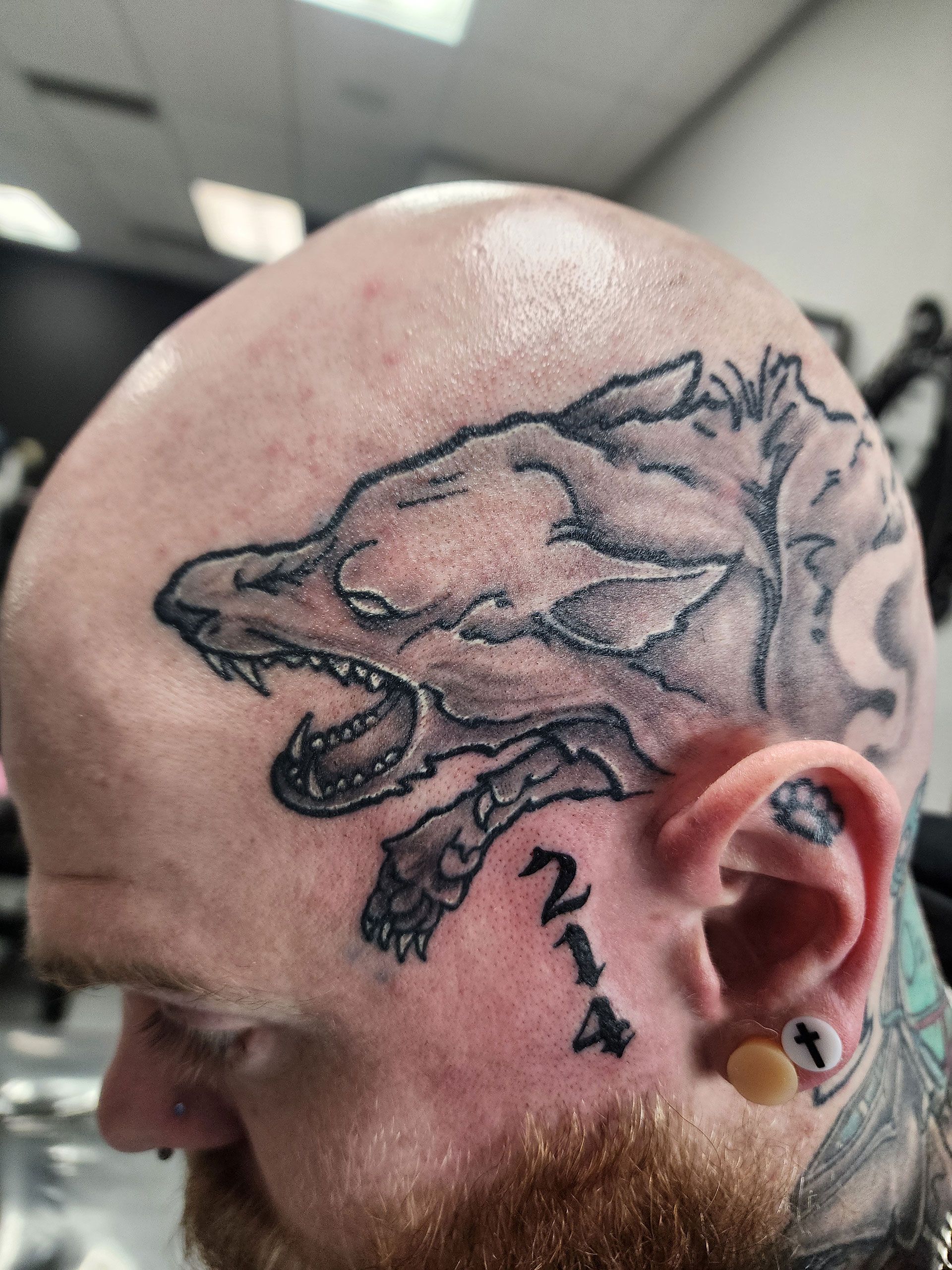 A man has a tattoo of a wolf on his head