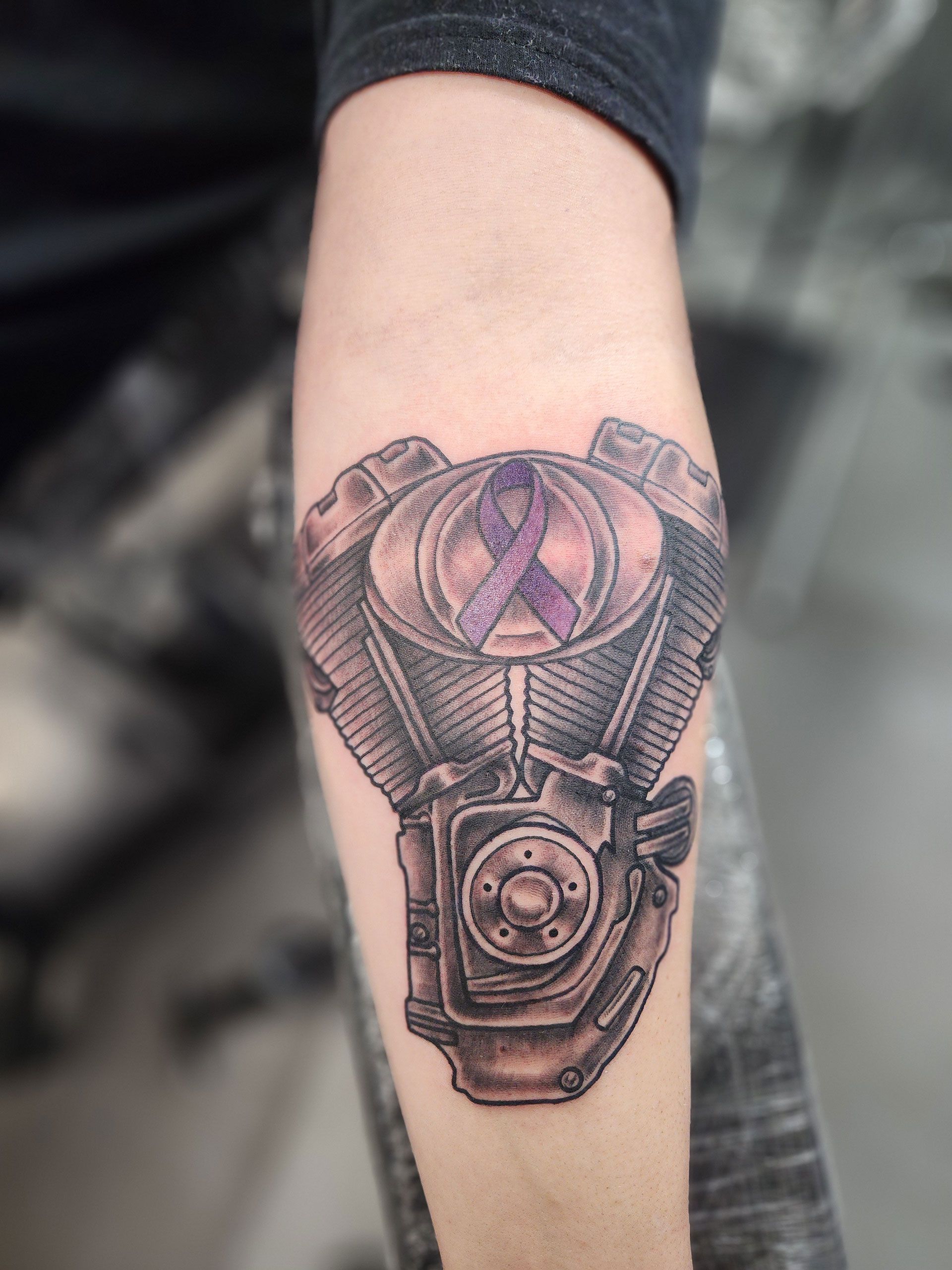 A person has a tattoo of a motorcycle engine on their arm