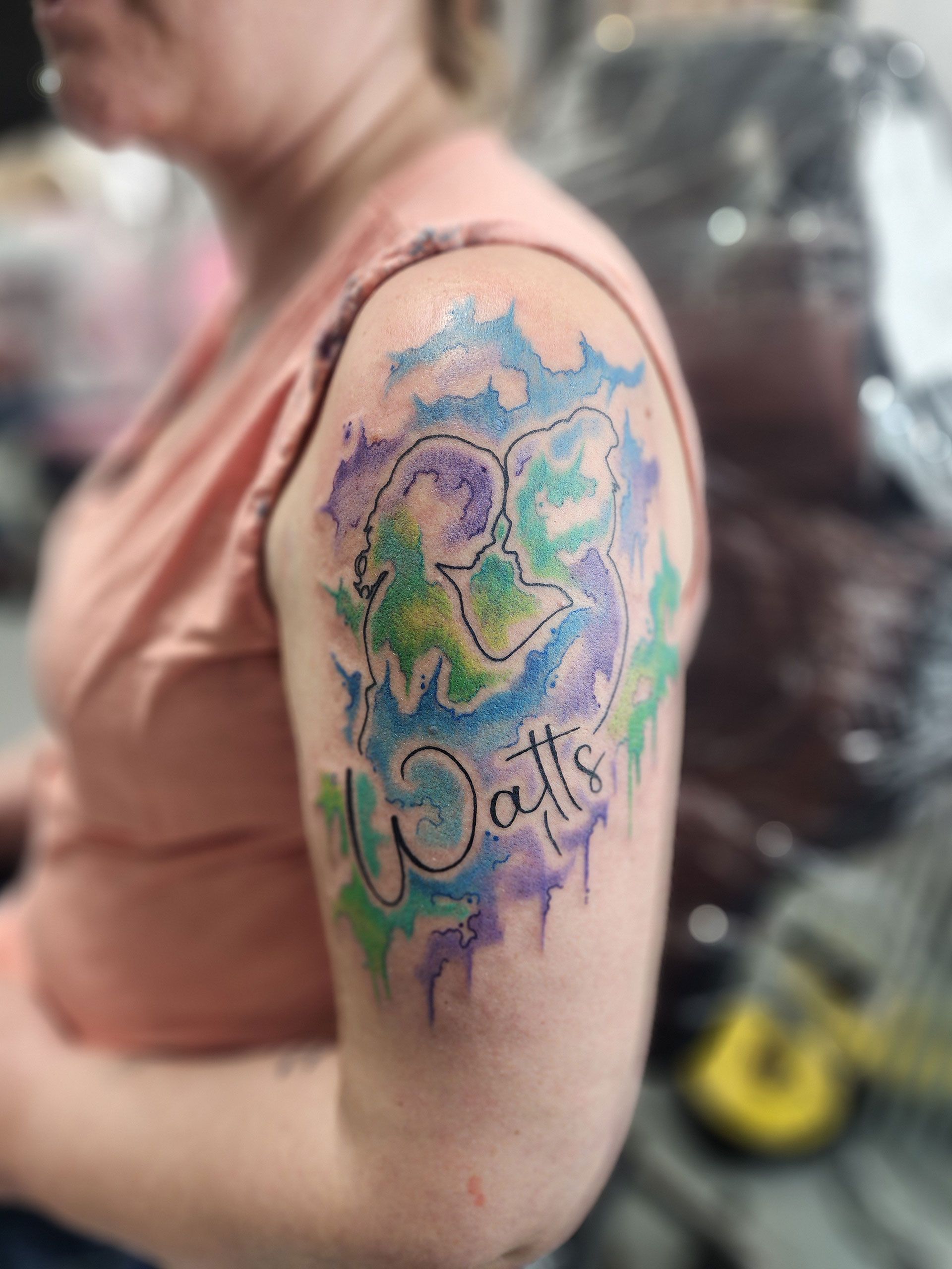 A woman has a tattoo on her arm that says watts