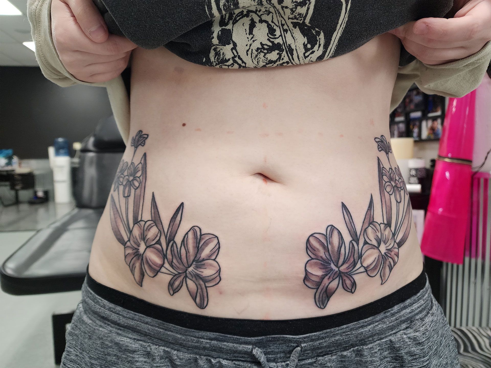 A woman has a tattoo of flowers on her stomach