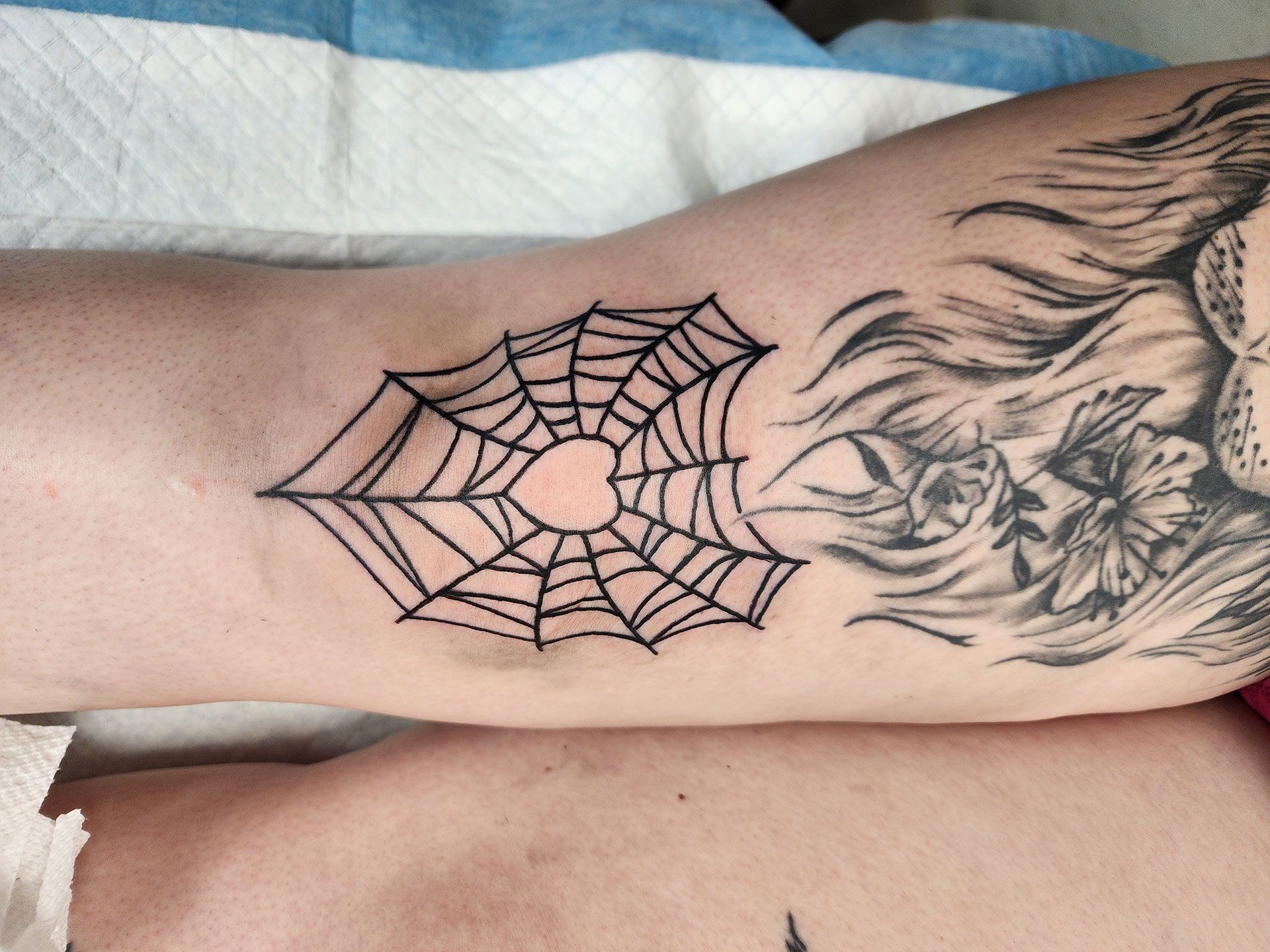 A person has a spider web tattoo on their arm
