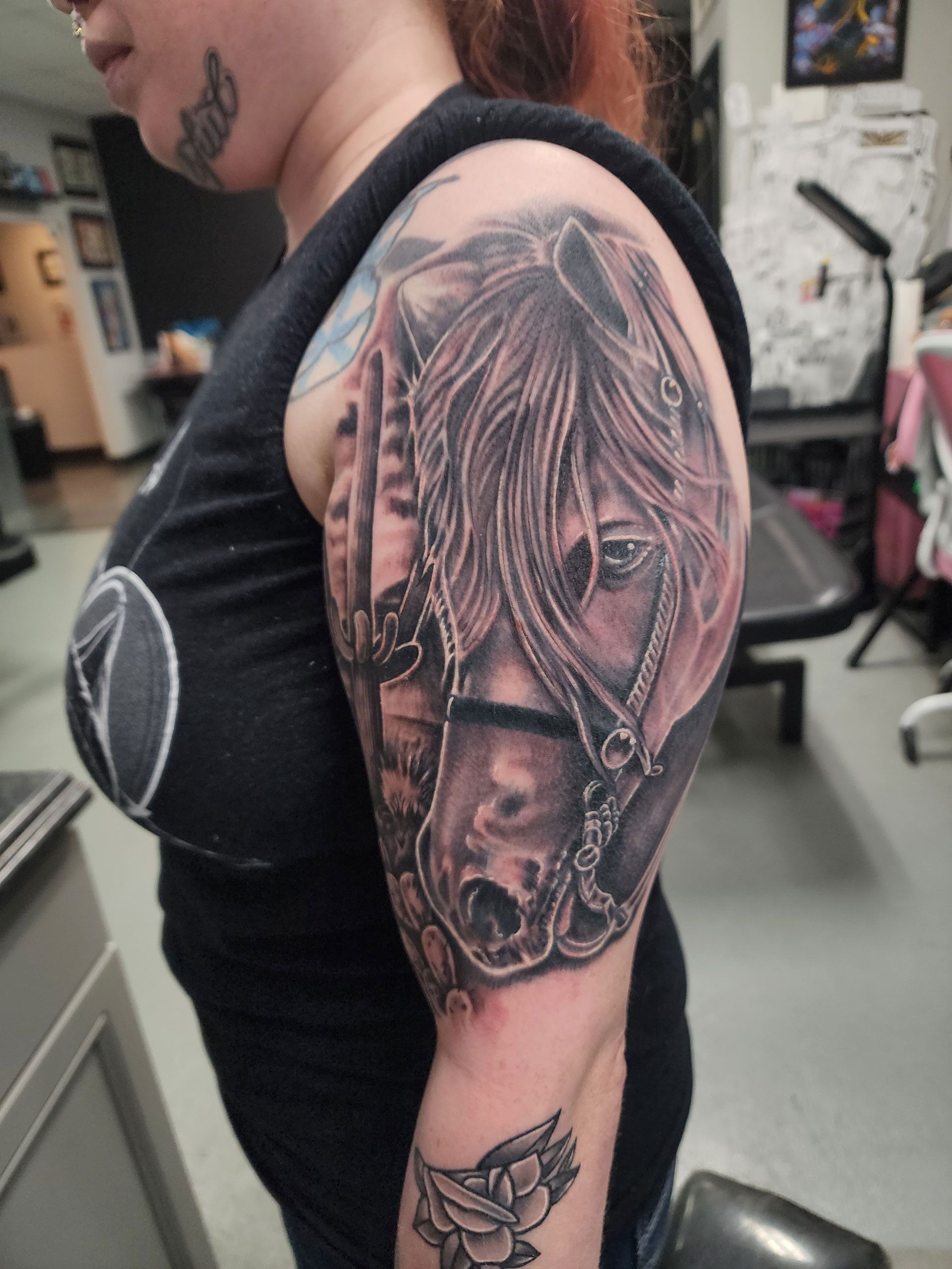 A woman has a tattoo of a horse on her arm