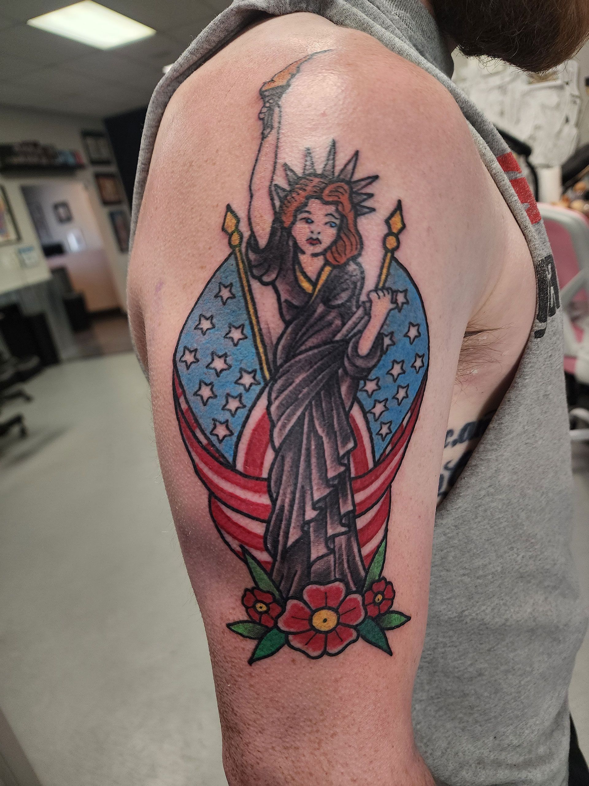 A man has a tattoo of the Statue of Liberty on his arm