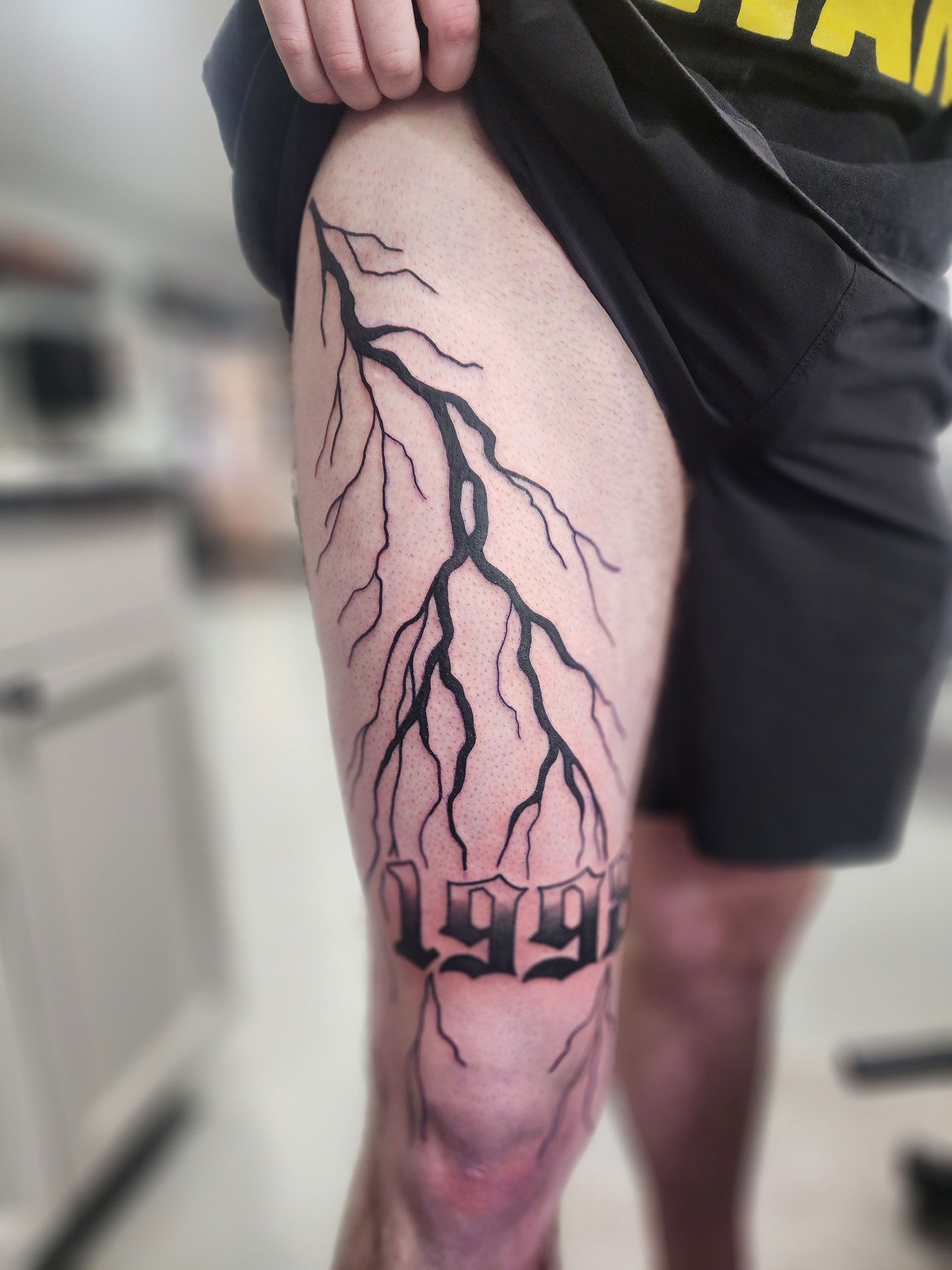 A person has a lightning bolt tattoo on their leg