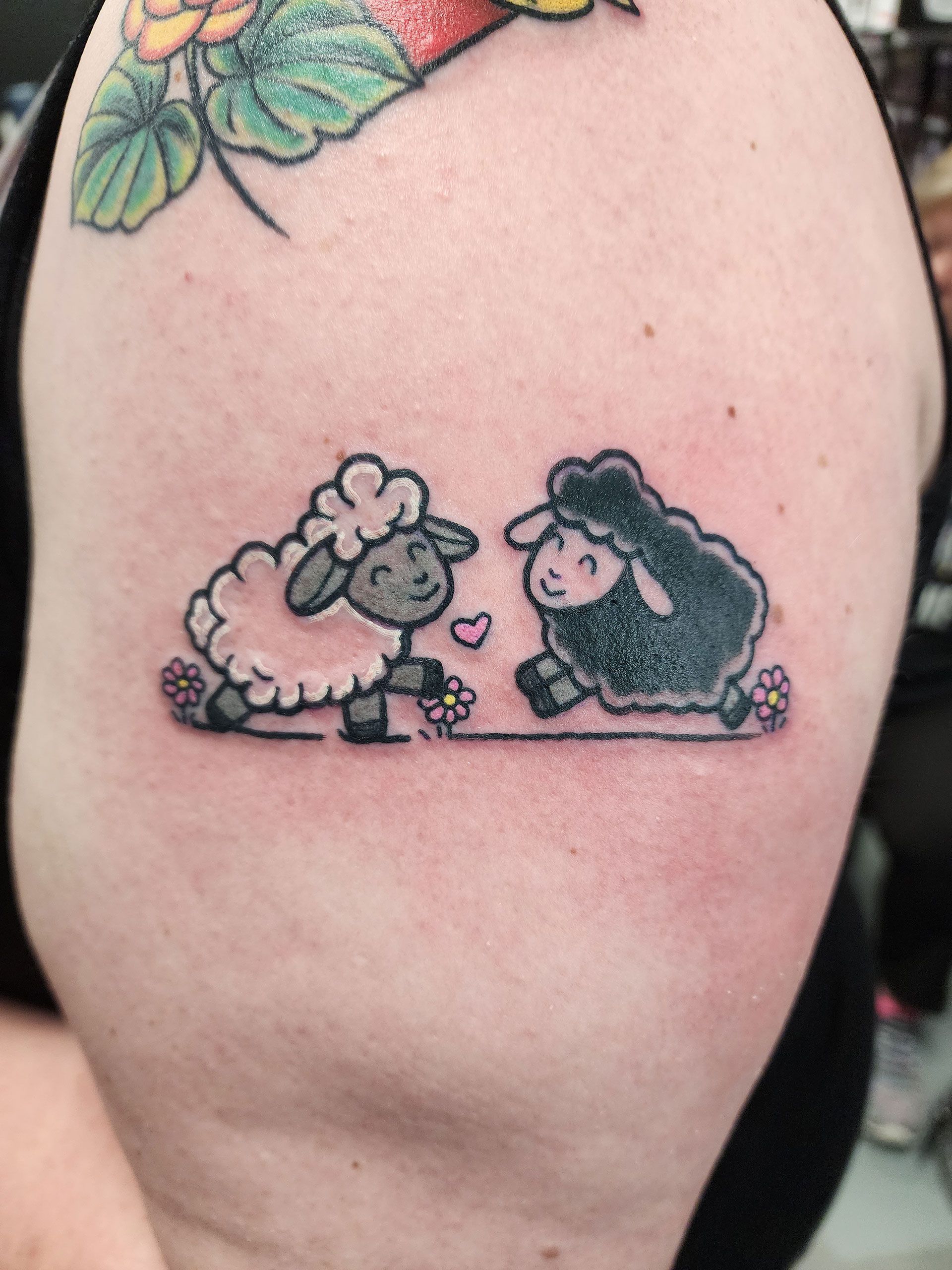 A person has a tattoo of two sheep on their arm
