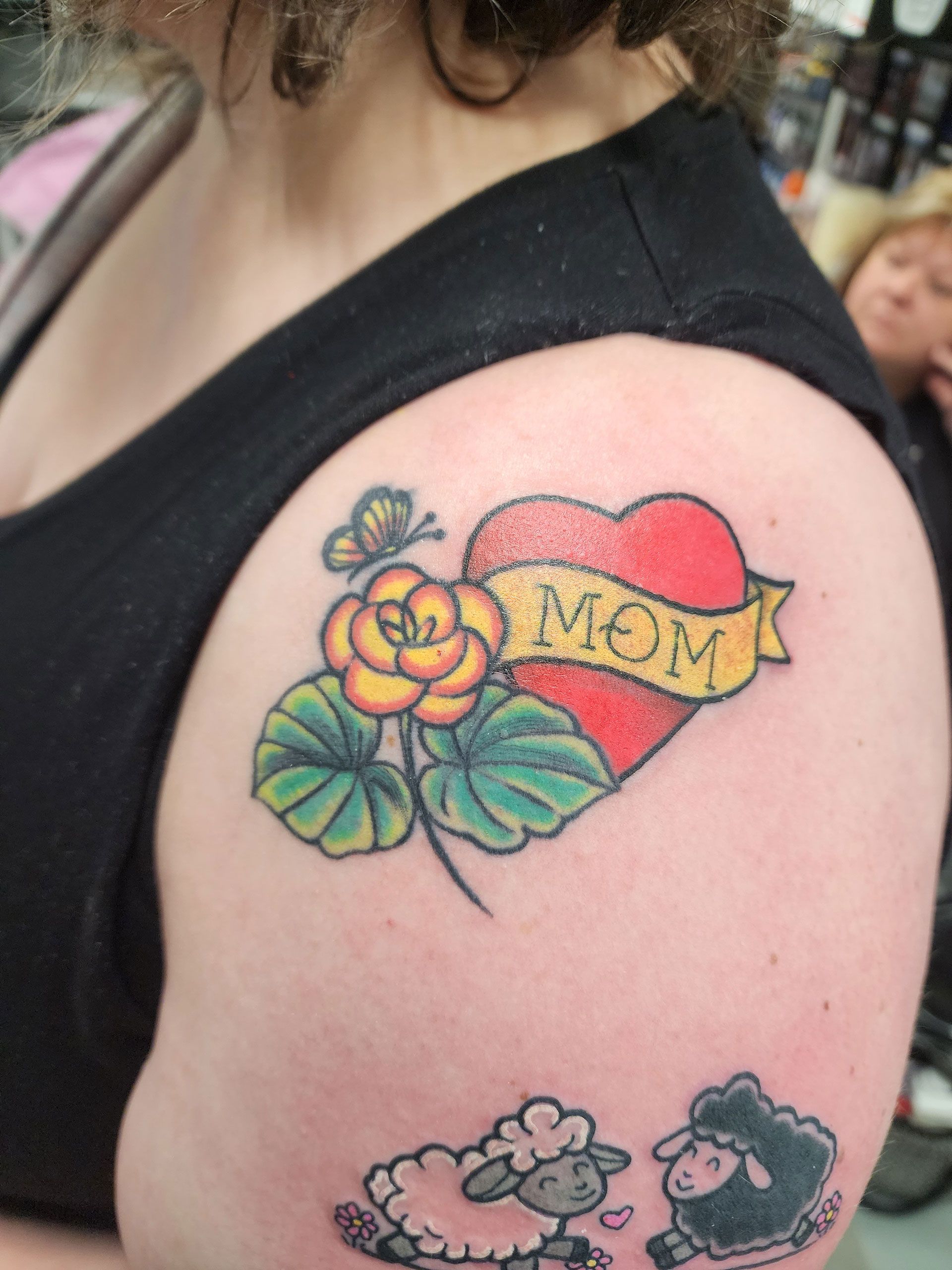 A woman has a tattoo of a heart with the word mom on it