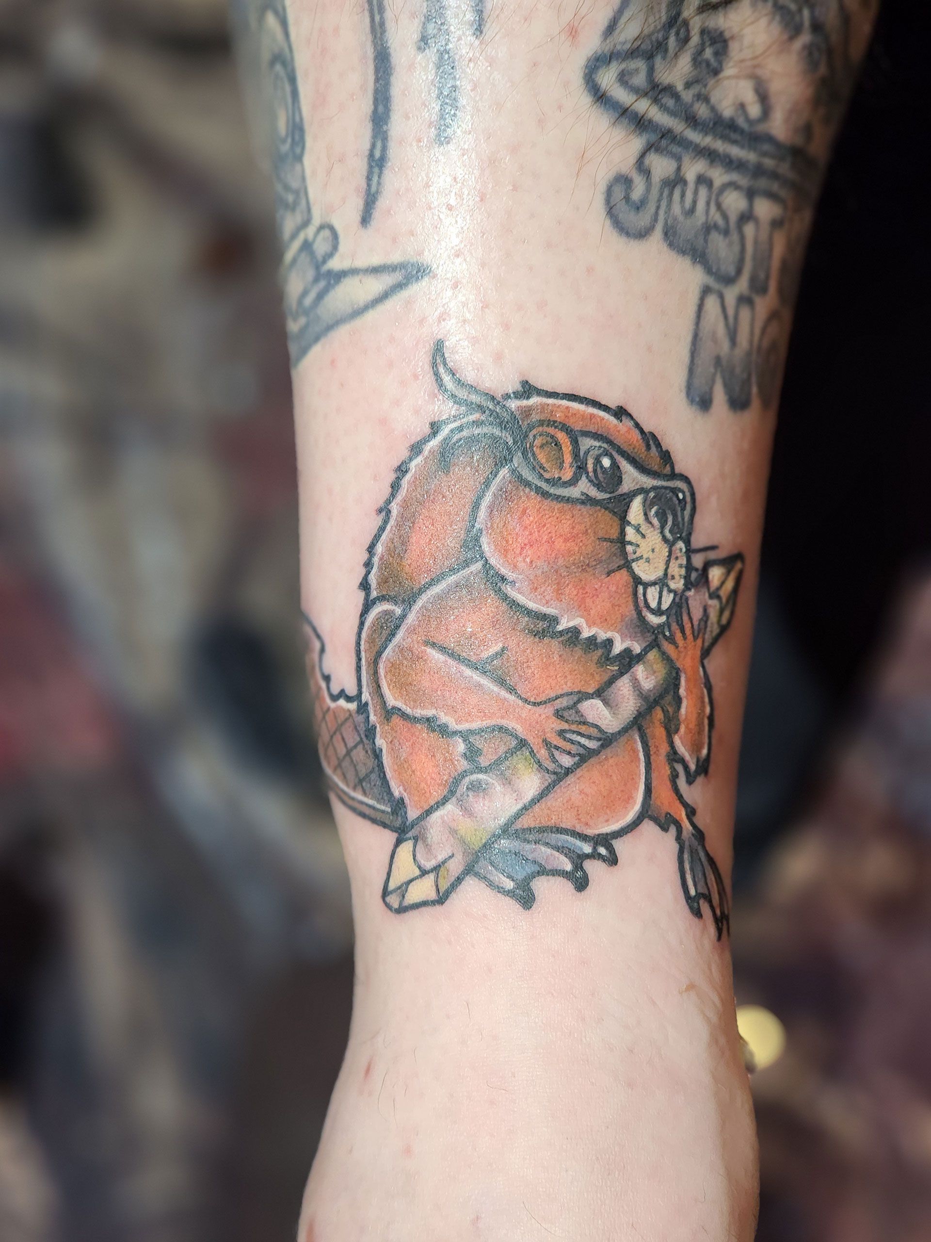 A person has a tattoo of a beaver wearing sunglasses