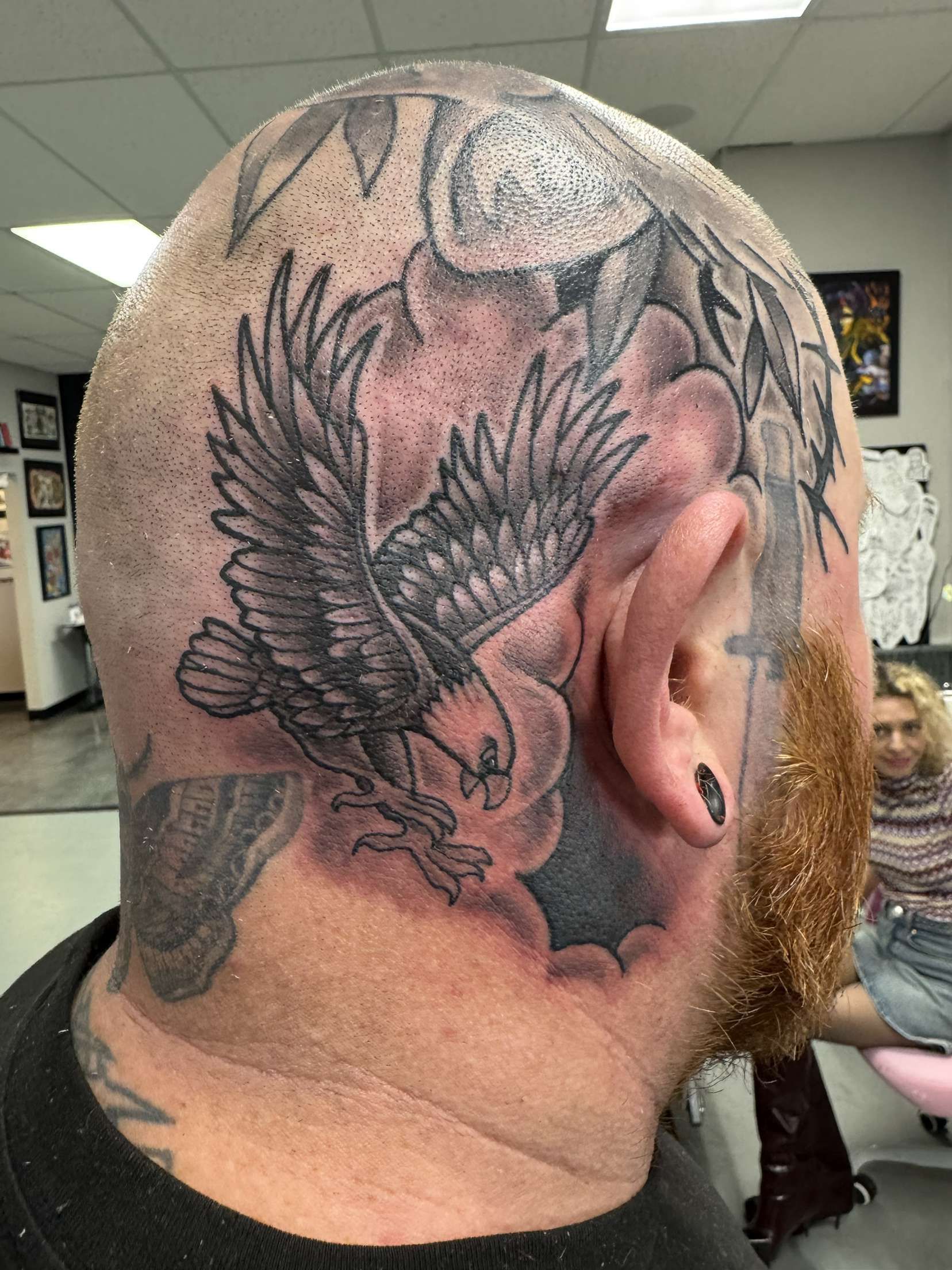 A man has a tattoo of an eagle on his head and neck