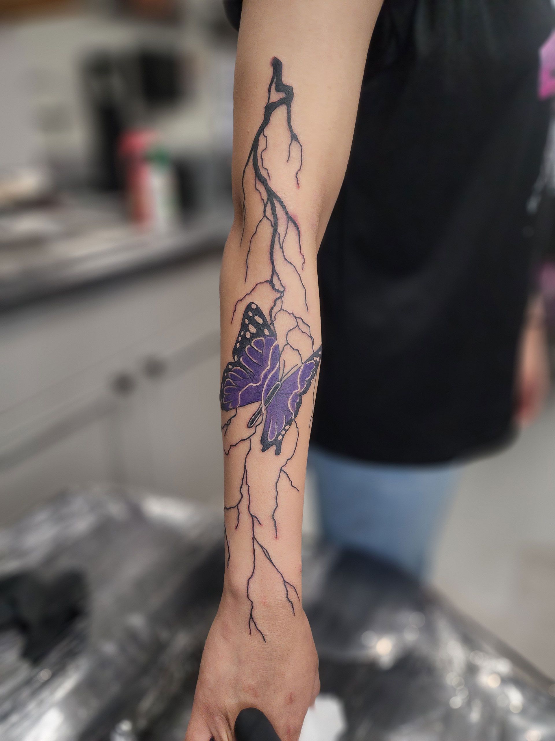 A thunder striking purple butterfly tattoo on arm