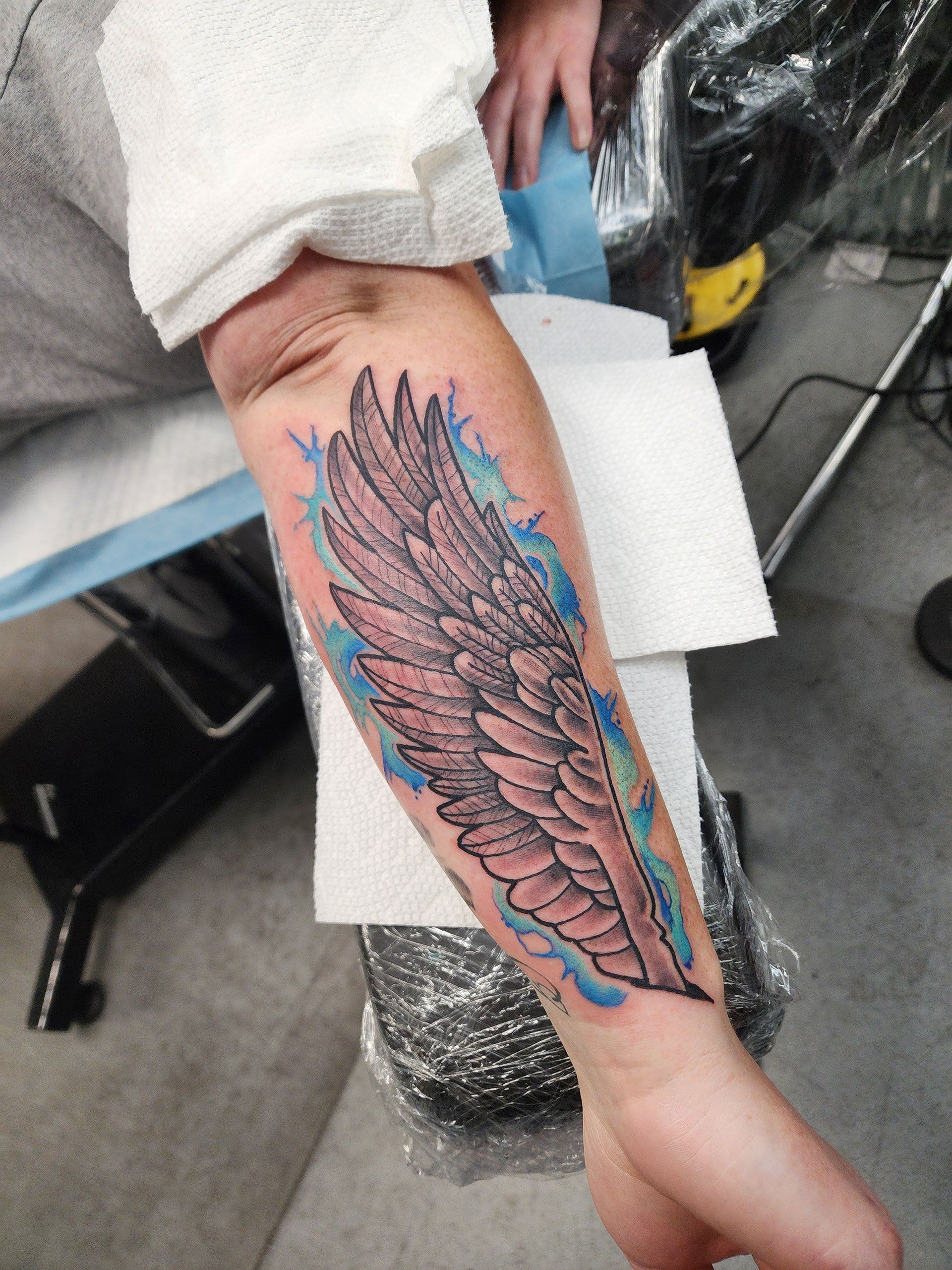 A person has a tattoo of a wing on their arm